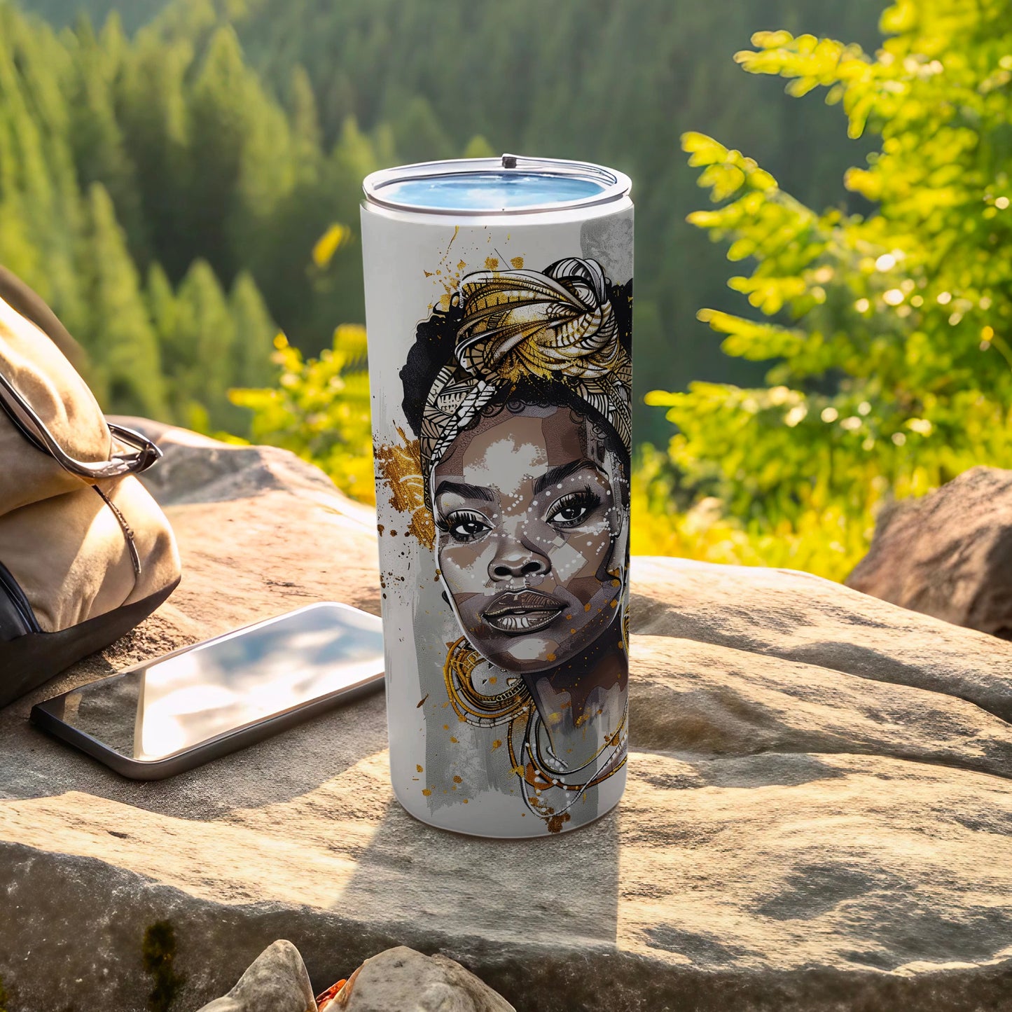 Tumbler with African woman's portrait and gold accents, set outdoors.