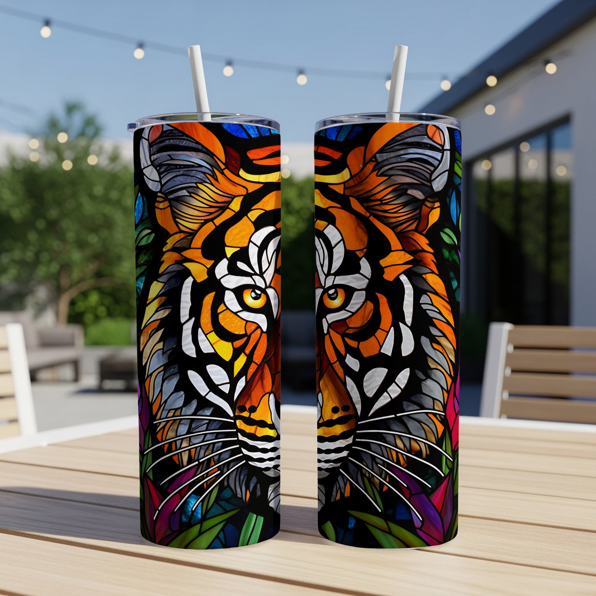 Two tumblers with a stained-glass tiger face design stand on a table outdoors.