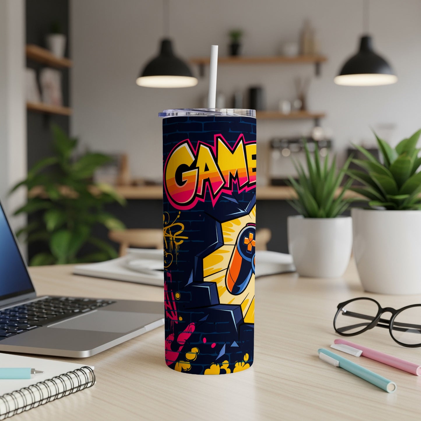 Graffiti-style tumbler with "GAME" text and controller gear on a desk.