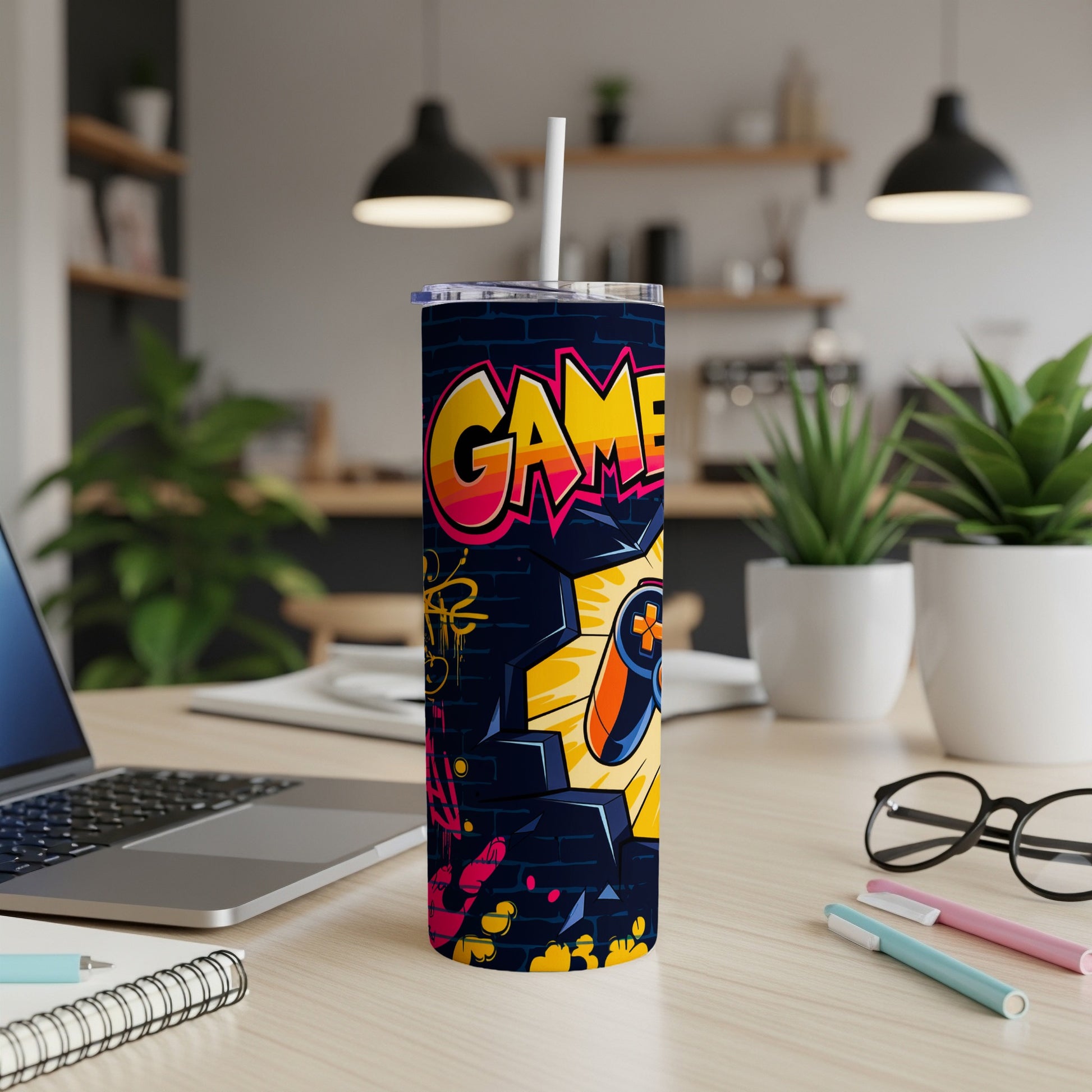 Graffiti-style tumbler with "GAME" text and controller gear on a desk.
