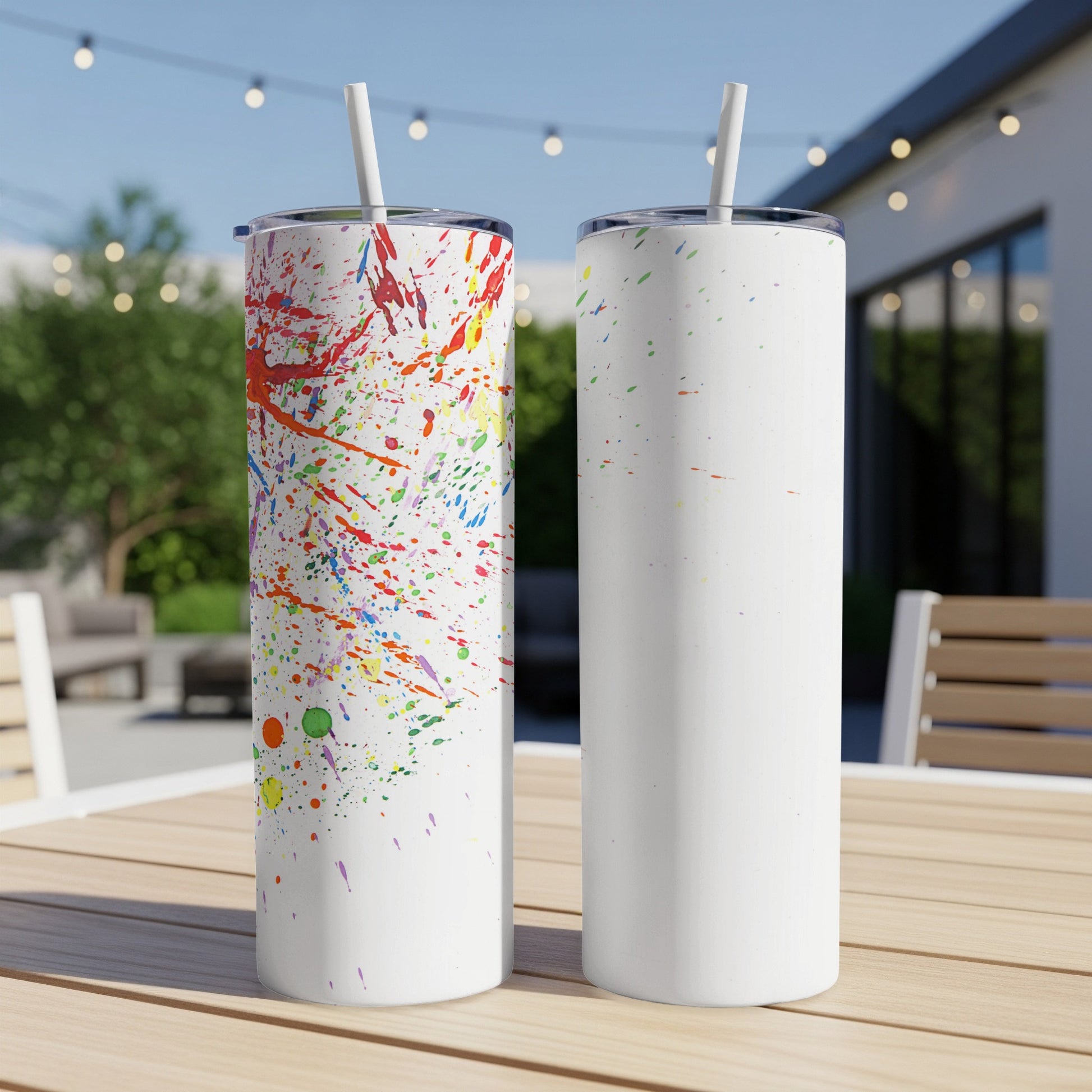 Two tumblers on a table, one with colorful paint splatters, the other blank.