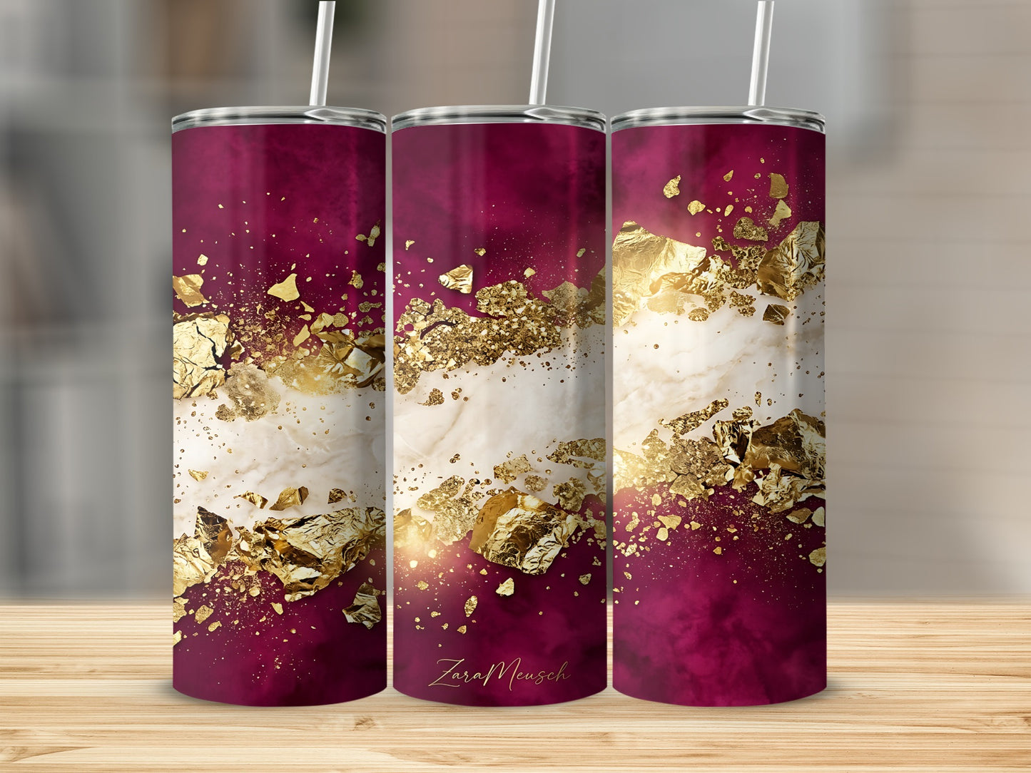 Burgundy and gold marble tumbler with straw on a wooden surface.