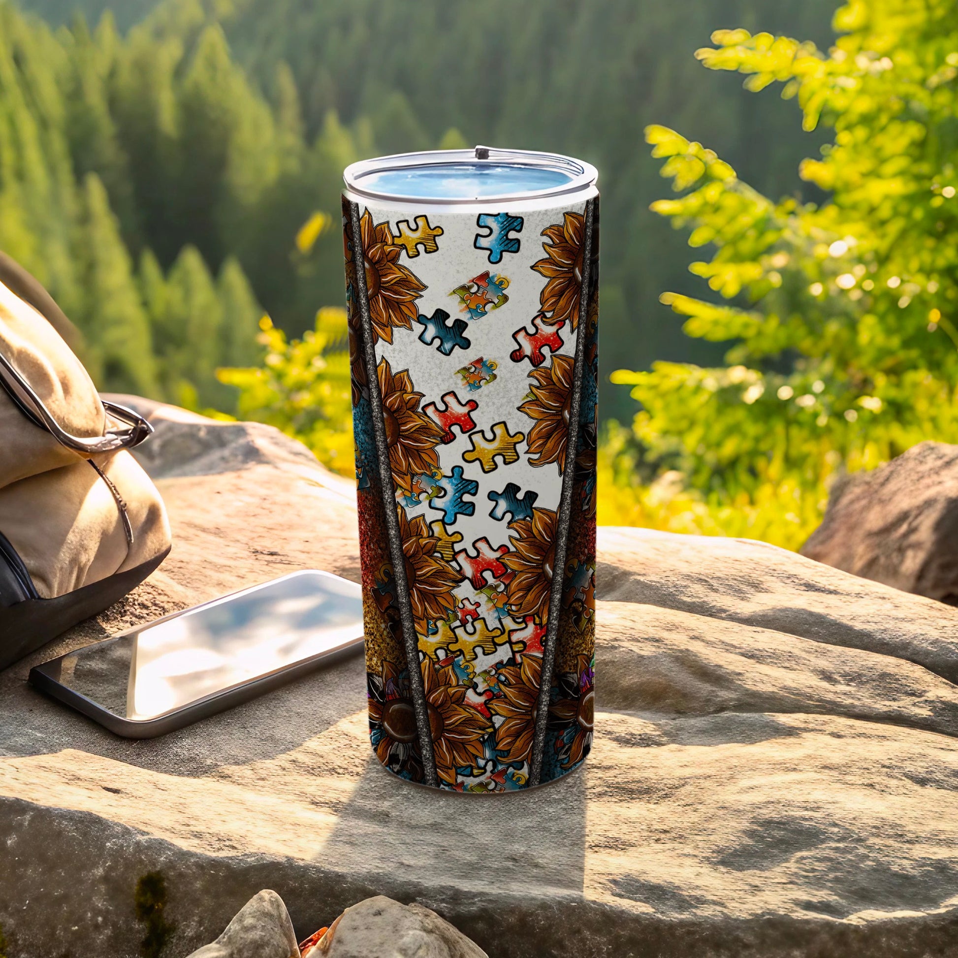 Tumbler with sunflower and puzzle piece pattern on a rock.