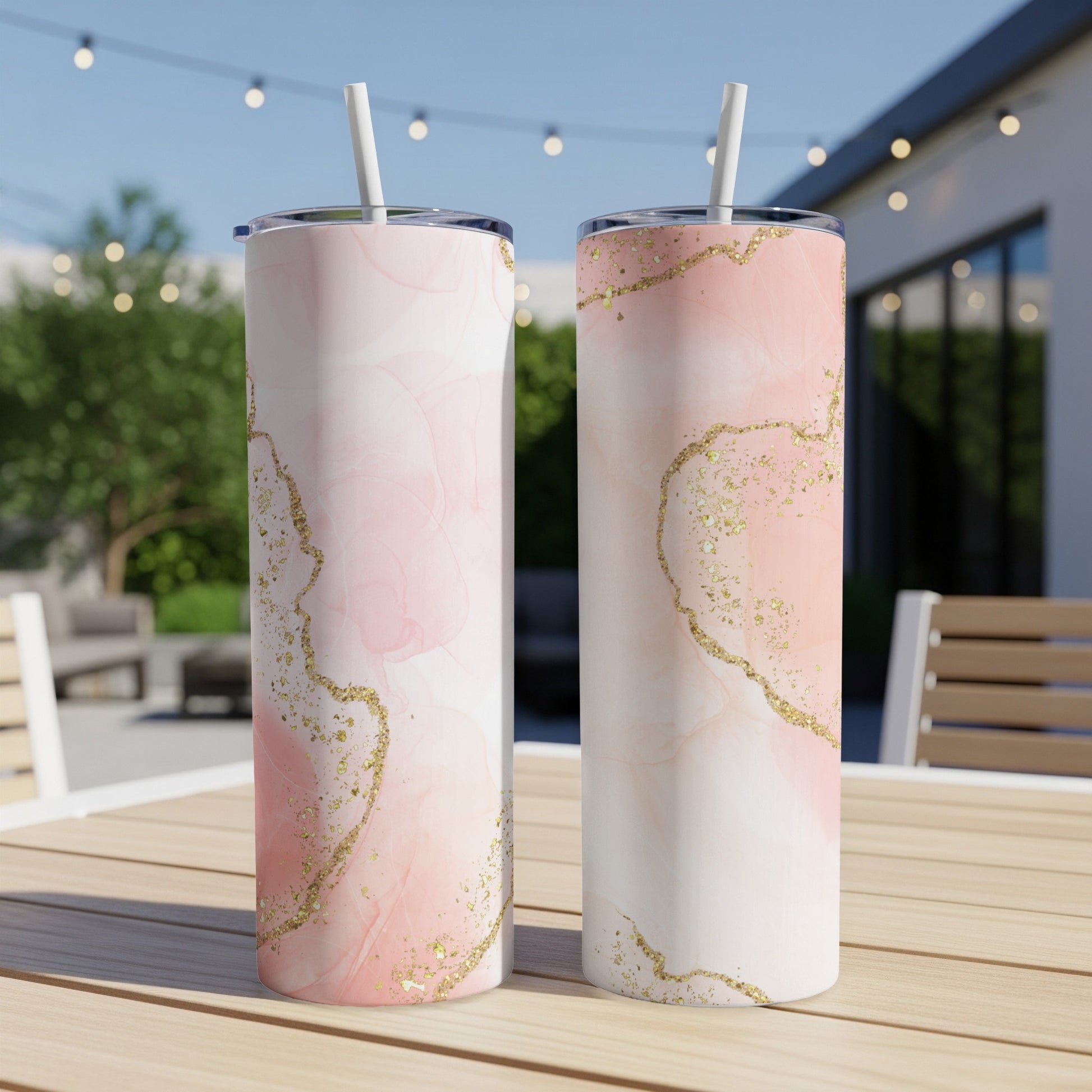 Two tall tumblers with pink marble and gold glitter design on a wooden table.