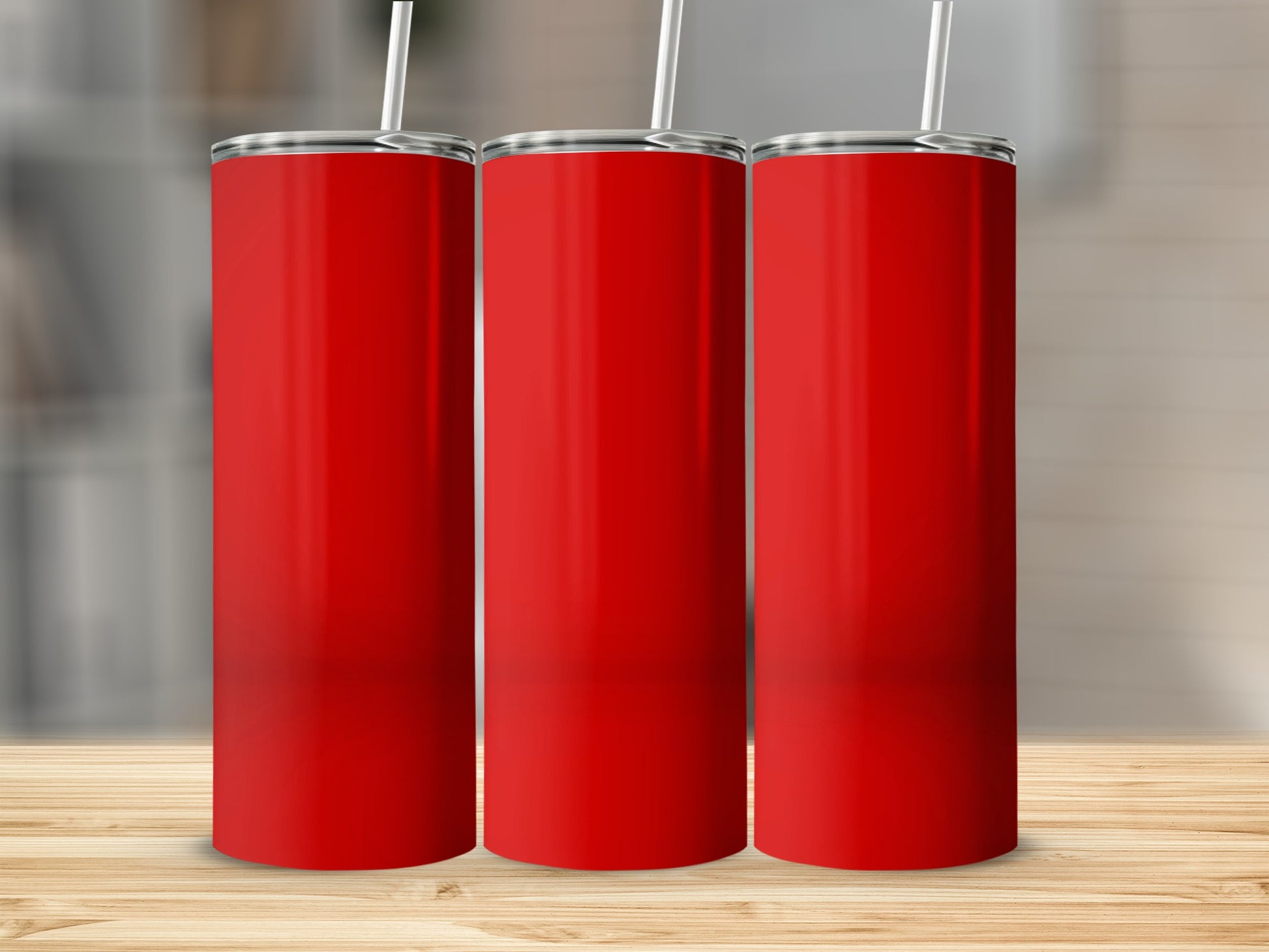 Three red tumblers with white straws stand on a wooden surface.