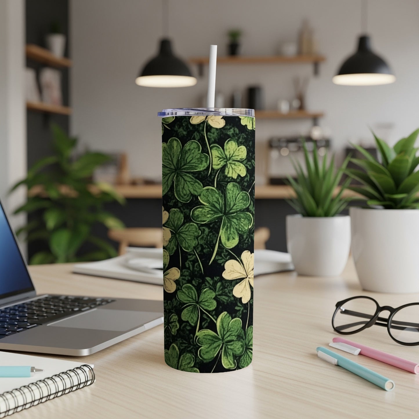 Green shamrocks on a dark background printed on a white tumbler with a straw.