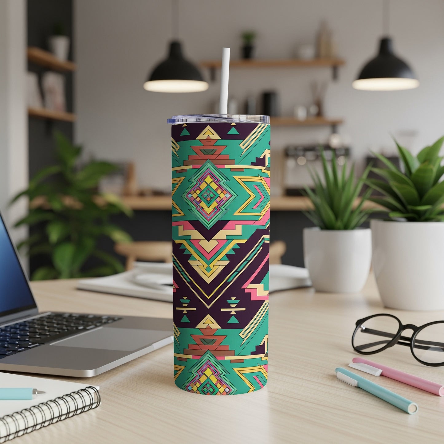 Tumbler with geometric Southwestern pattern on a desk with a laptop.