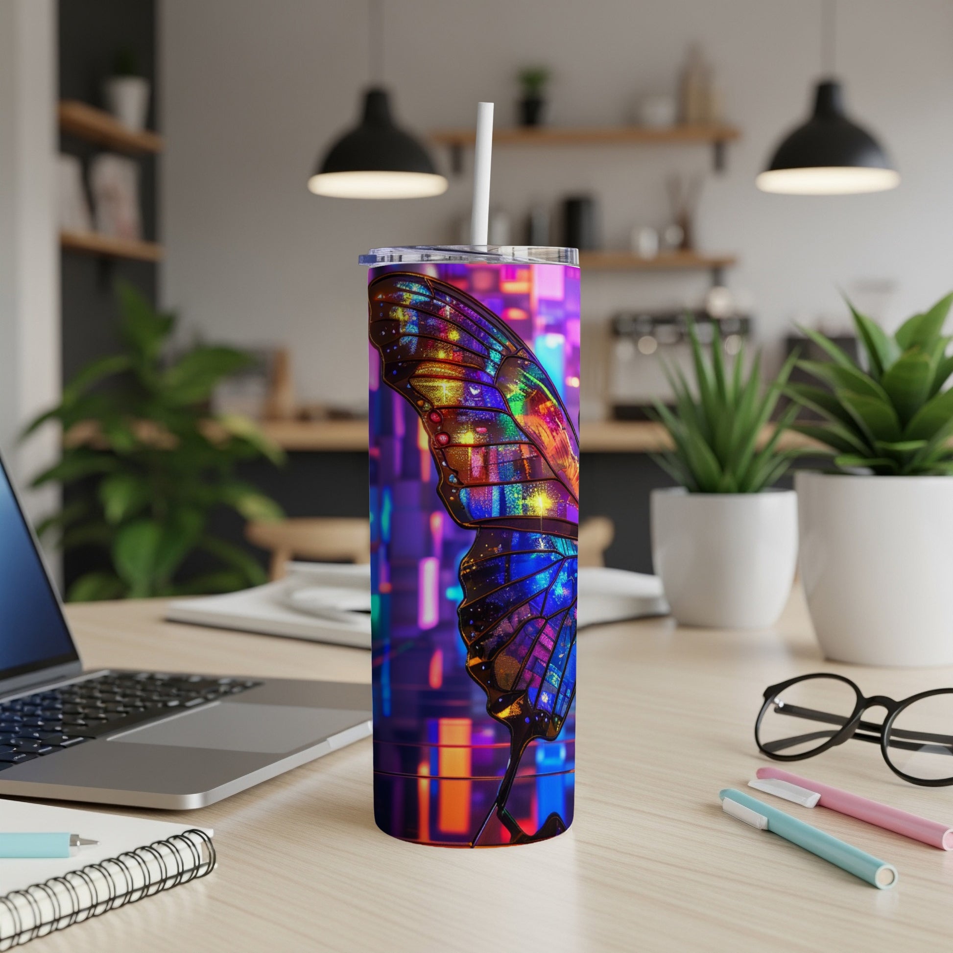 Tumbler with iridescent butterfly design and straw on desk.