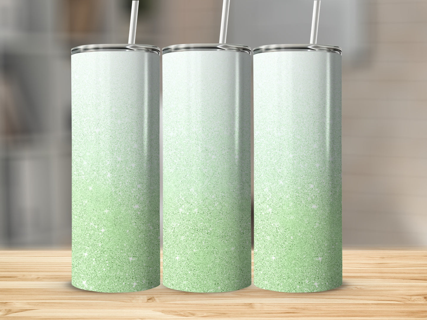 Three tall, glitter-covered tumblers with gradient green and white designs.