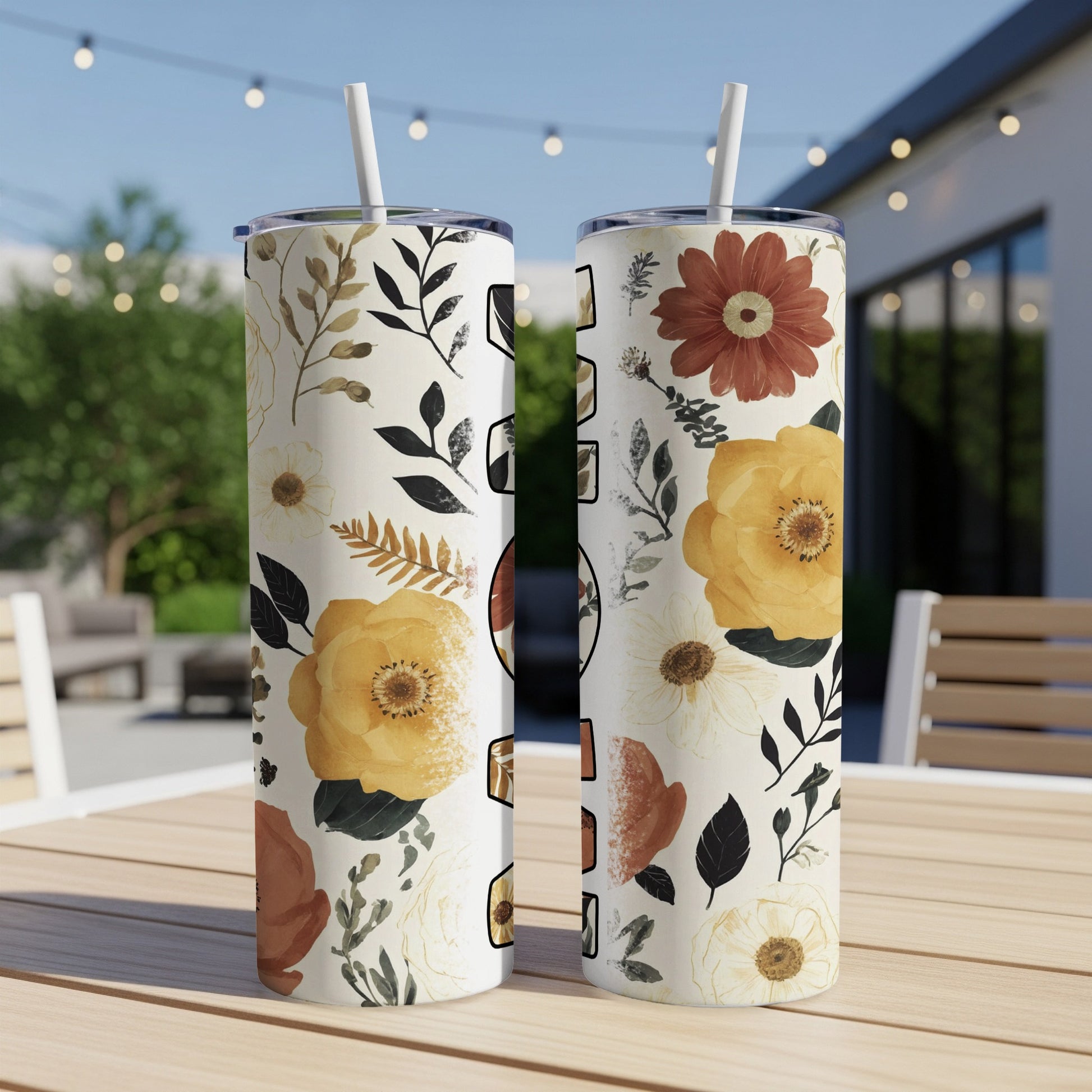 Two tumblers with floral and botanical designs sit on a table.
