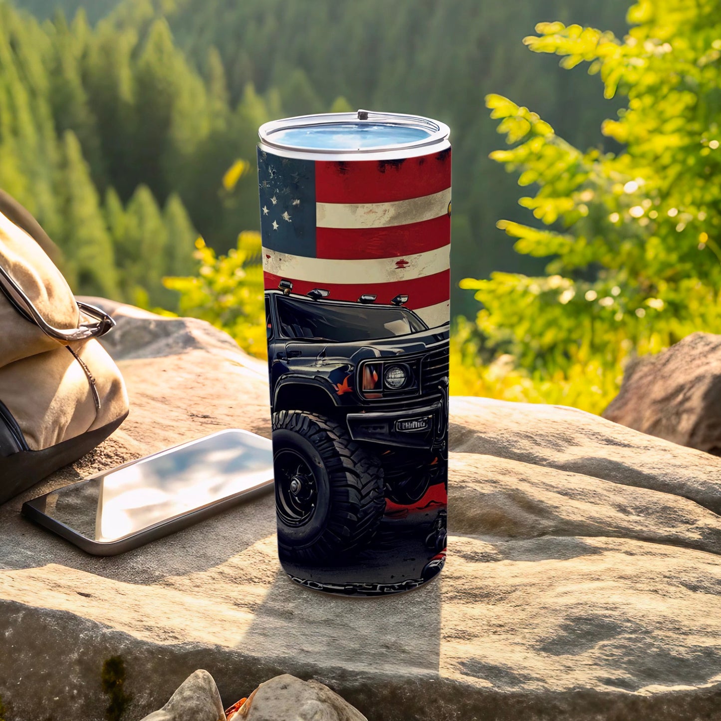 Black truck on American flag tumbler resting on rocks outdoors.
