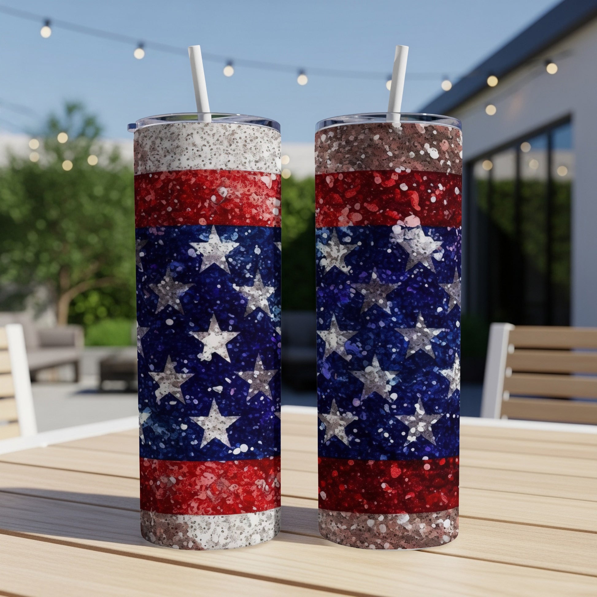 Two tall tumblers with a glittery American flag design stand on a wooden table.