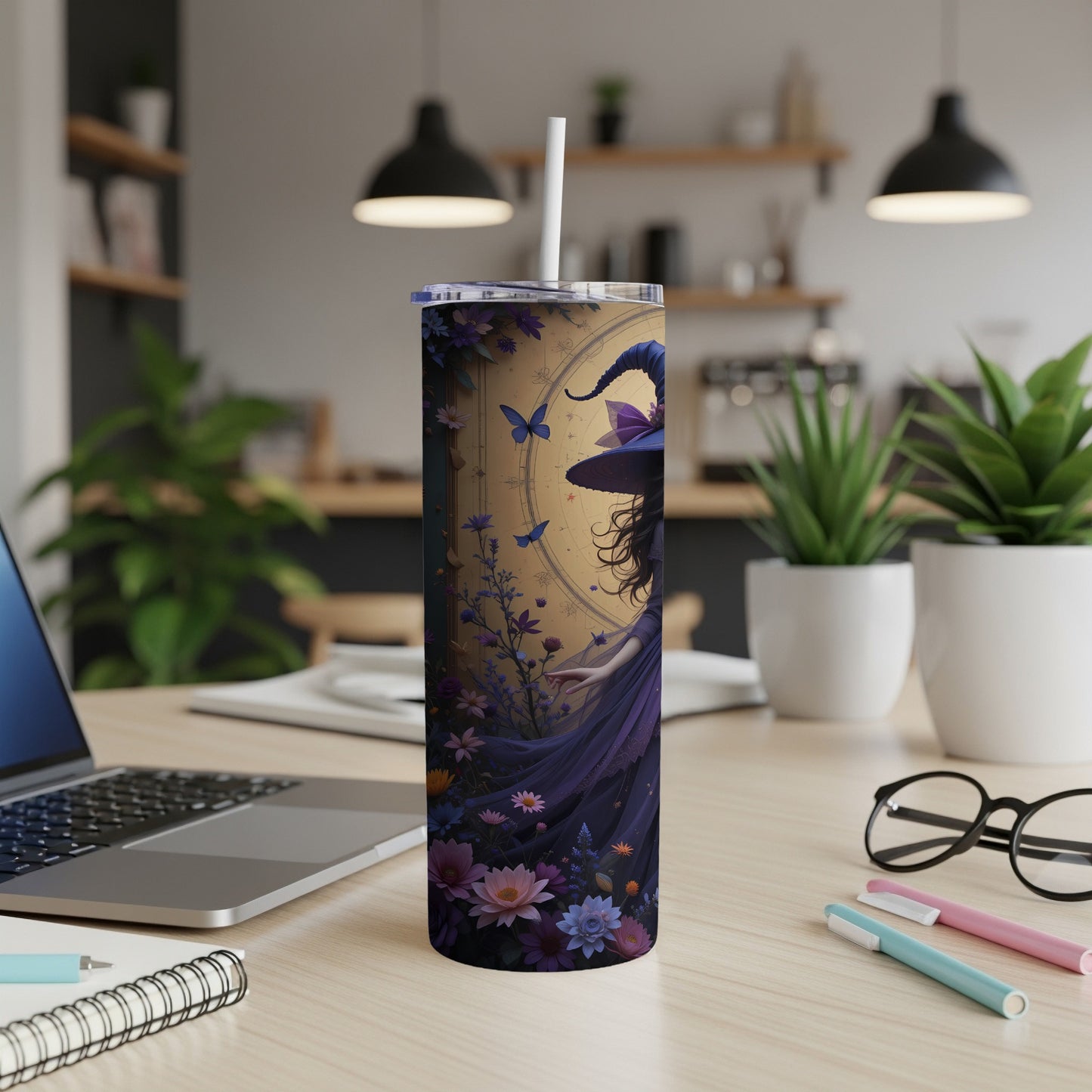 Tall tumbler with purple witch and floral design, placed on a desk.