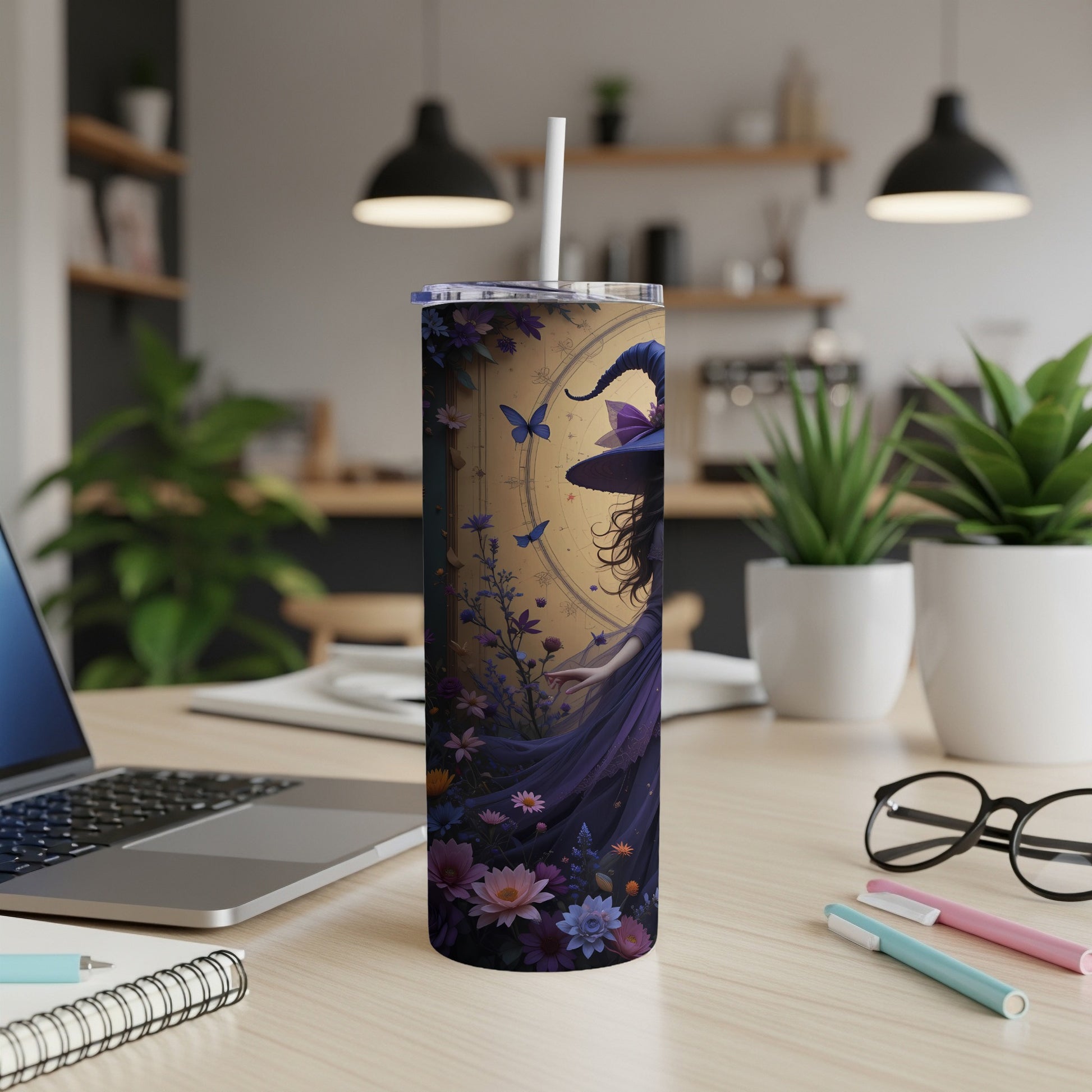 Tall tumbler with purple witch and floral design, placed on a desk.