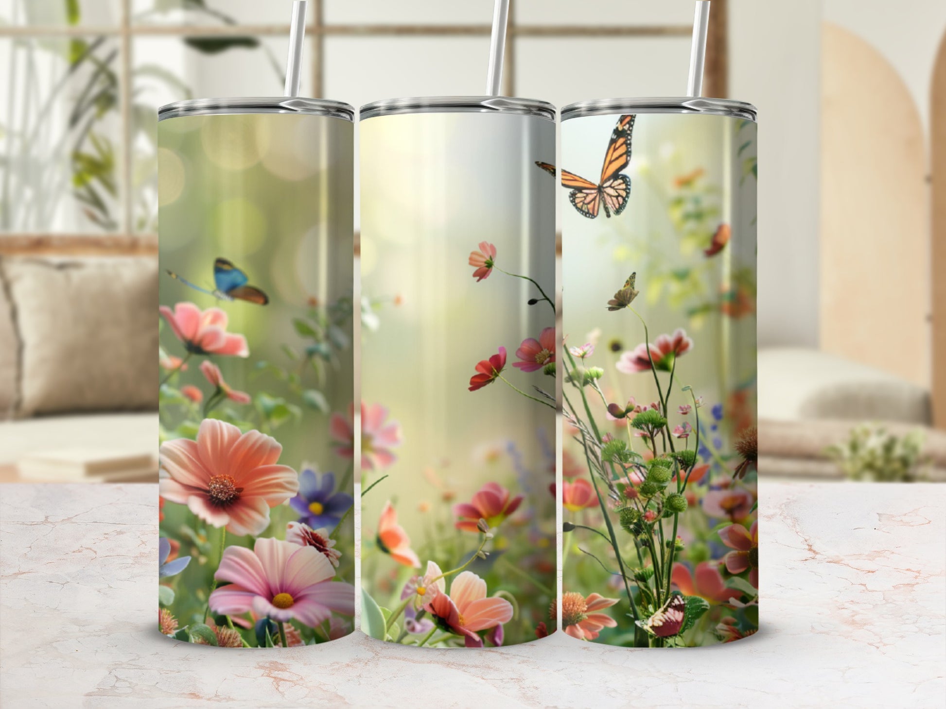 Three tumblers with a floral and butterfly design displayed on a marble countertop.