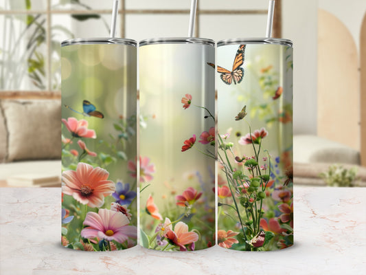 Three tumblers with a floral and butterfly design displayed on a marble countertop.