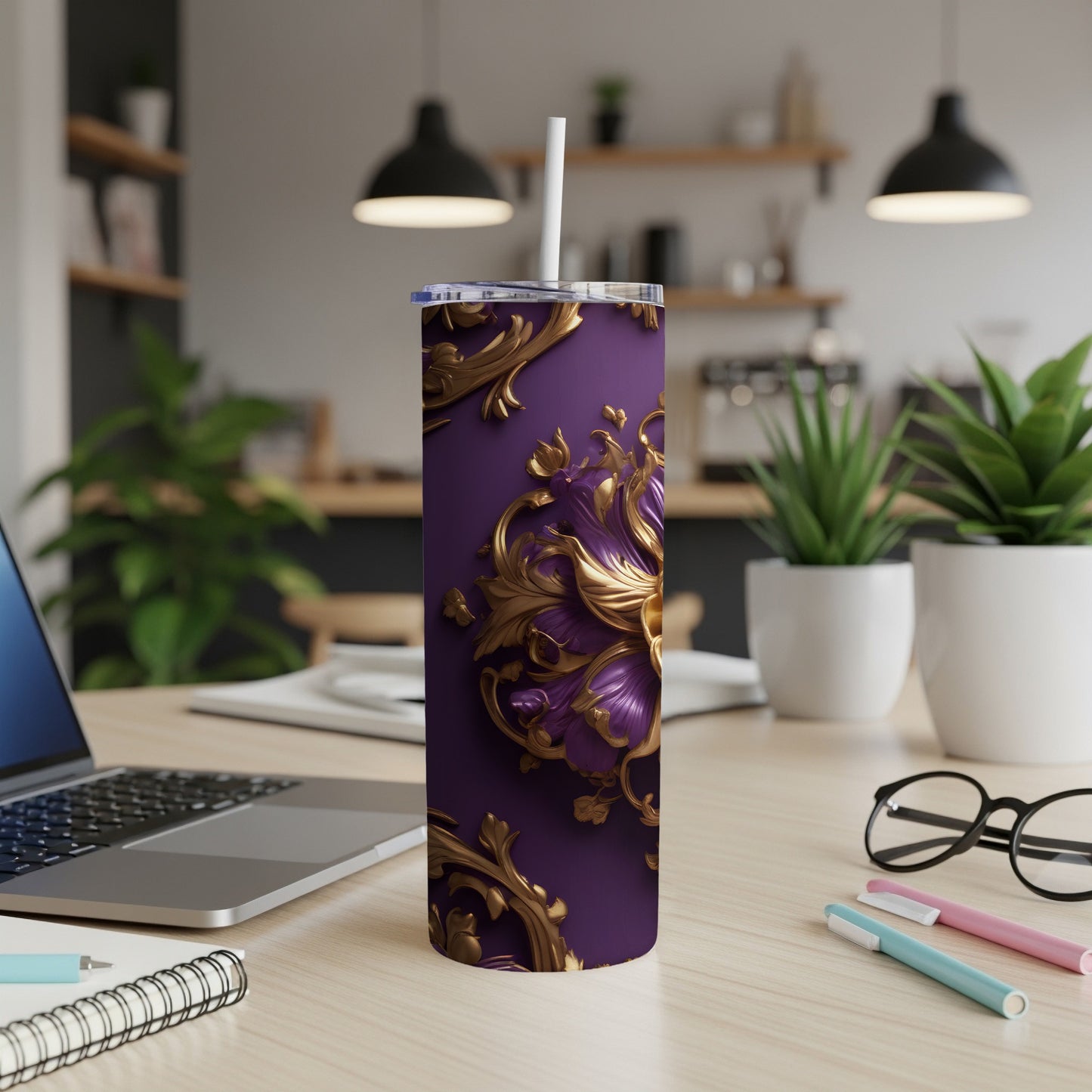 Purple tumbler with gold floral design on desk with laptop and pens.