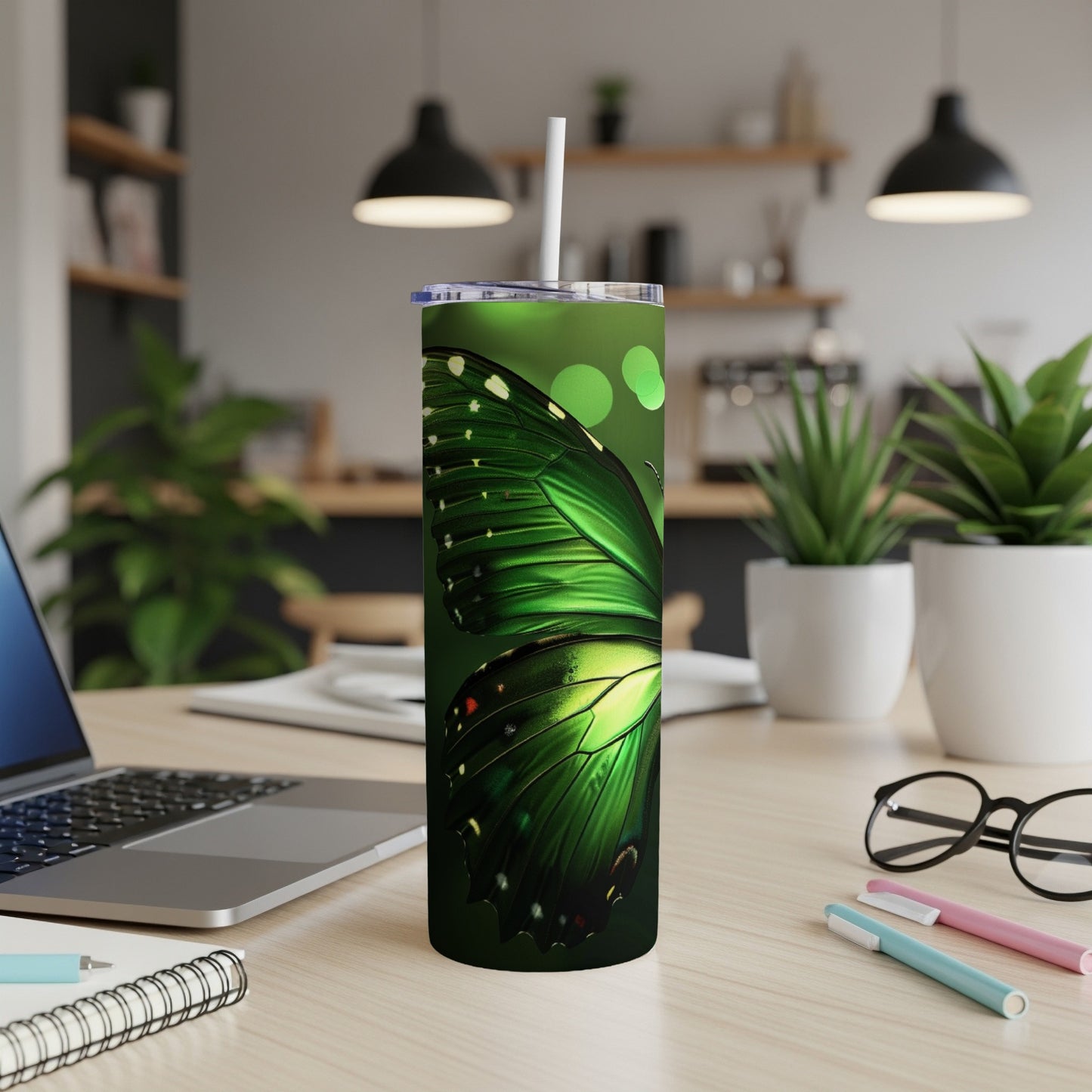 Green butterfly wing pattern on a tall, white tumbler with a straw.