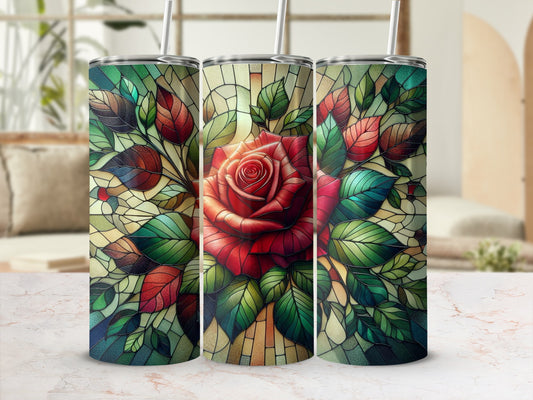 Red rose and green leaves stained glass tumbler designs on marble surface.