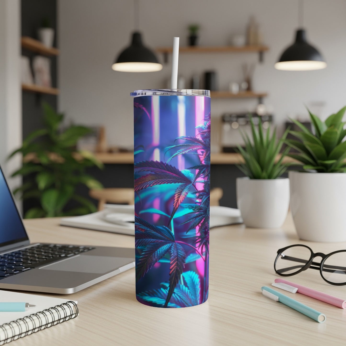 Blue and purple cannabis leaf tumbler with straw on a desk.