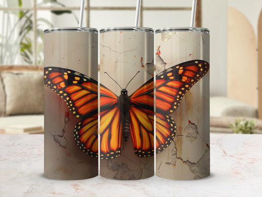 Three tumblers with monarch butterfly design on cracked plaster background.