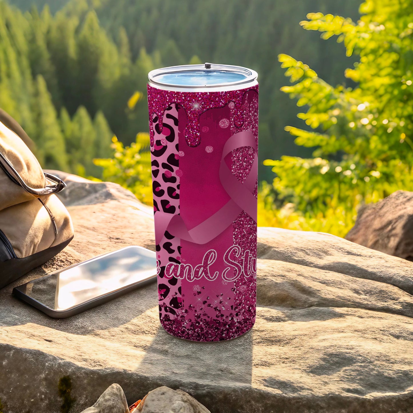 Pink tumbler with leopard print and awareness ribbon, resting on rocks.