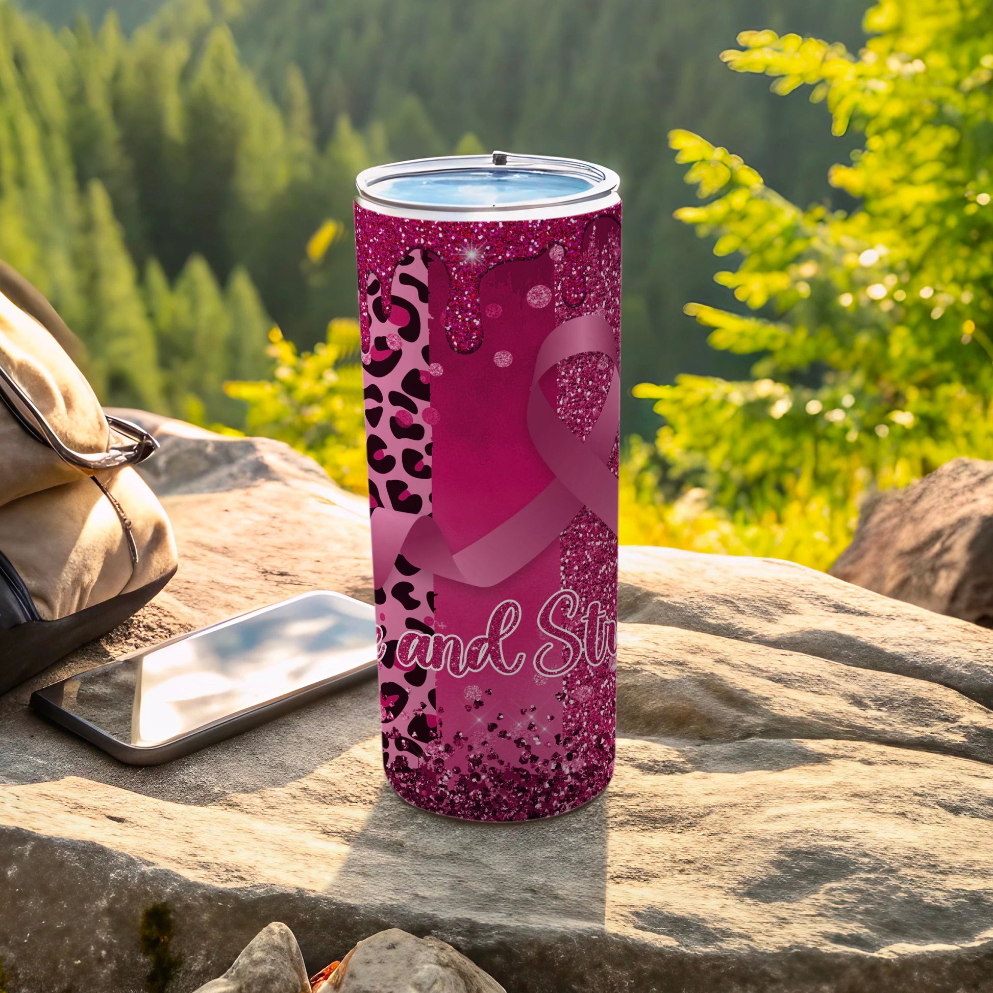 Pink tumbler with leopard print and awareness ribbon, resting on rocks.