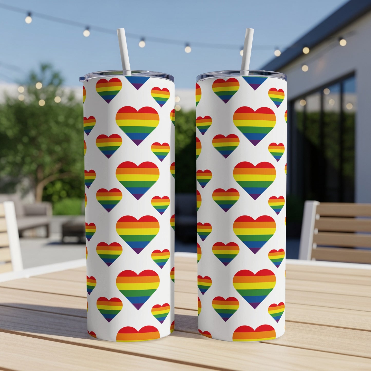 Two white tumblers with rainbow heart pattern on a wooden table.