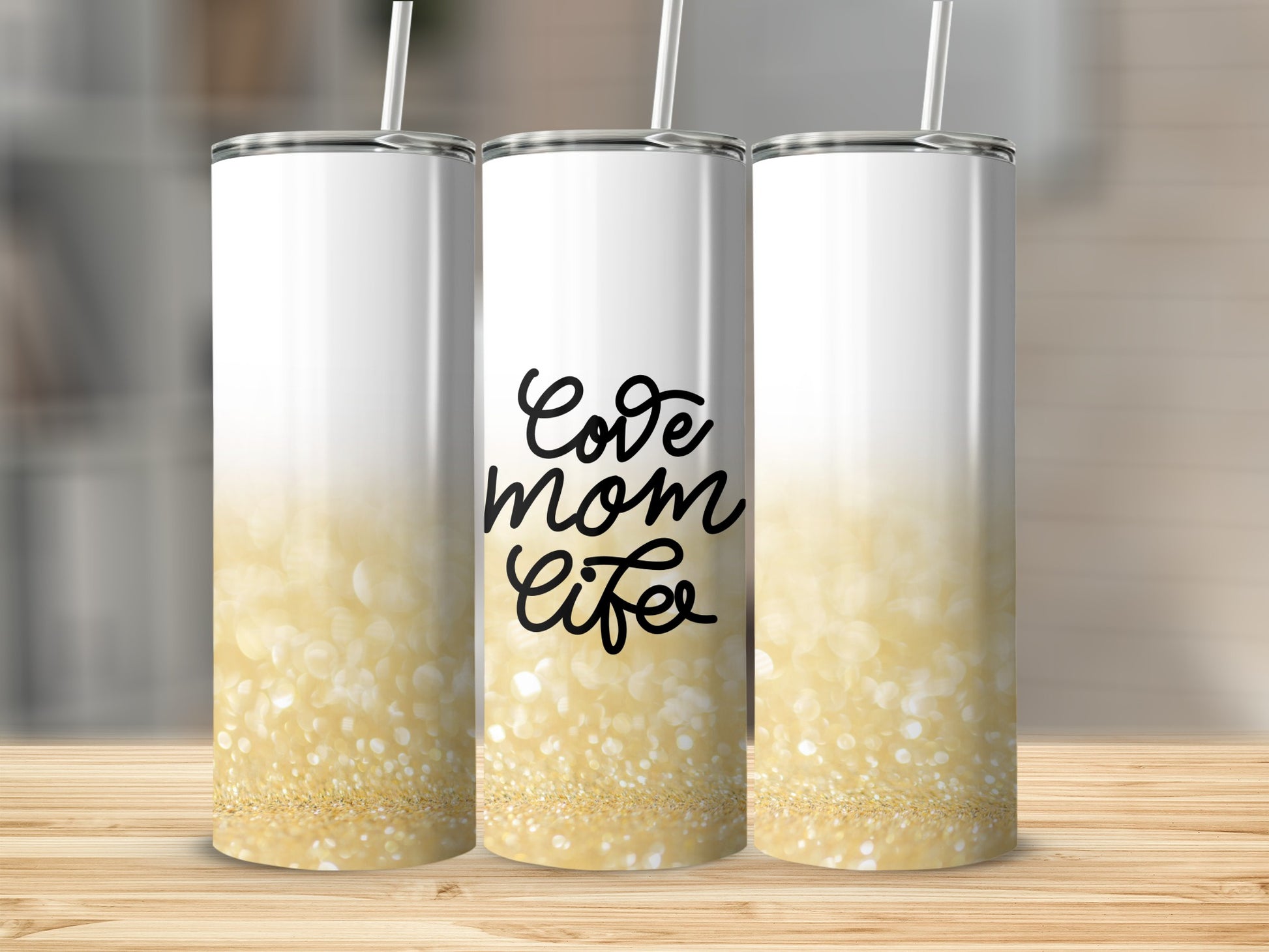 Three white tumblers with gold glitter at the bottom, one with "Love Mom Life" text.