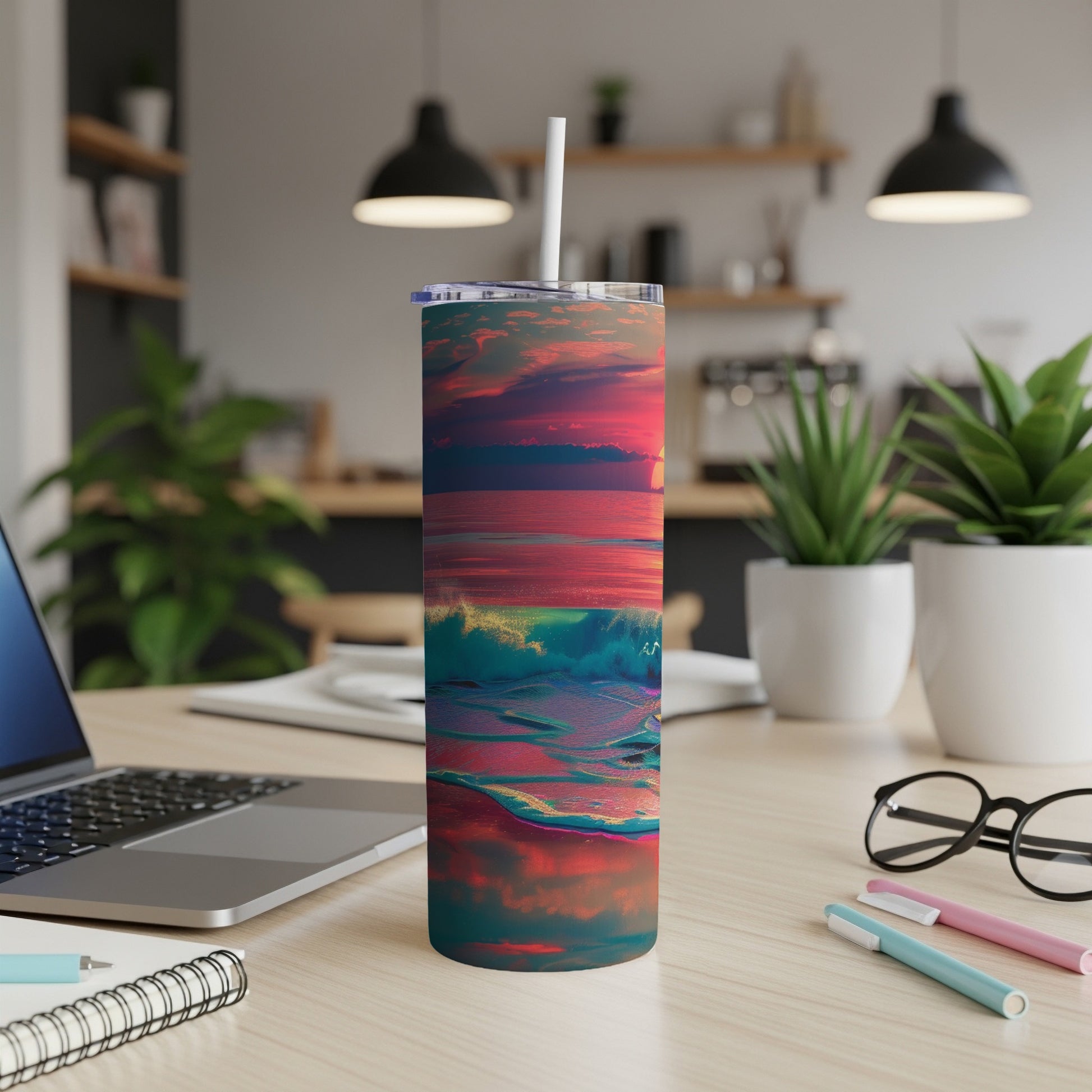 Tumbler with colorful ocean sunset design on a desk.