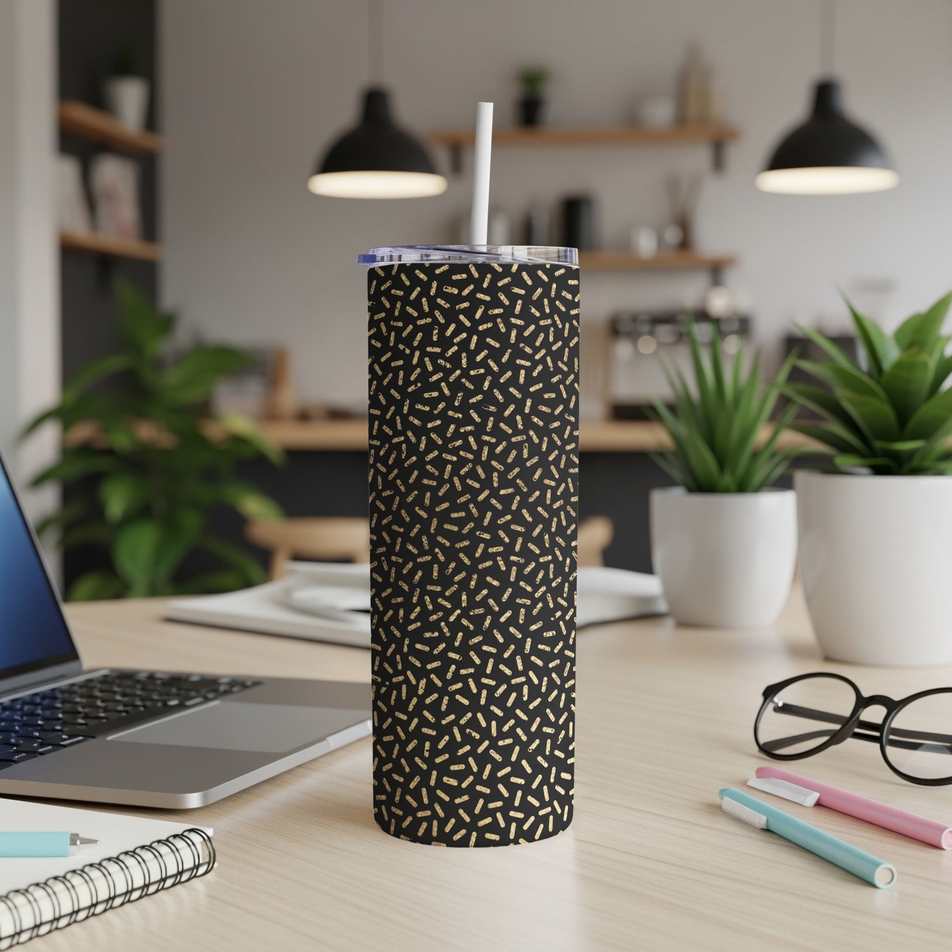 Black tumbler with gold sprinkle pattern, straw, and clear lid.