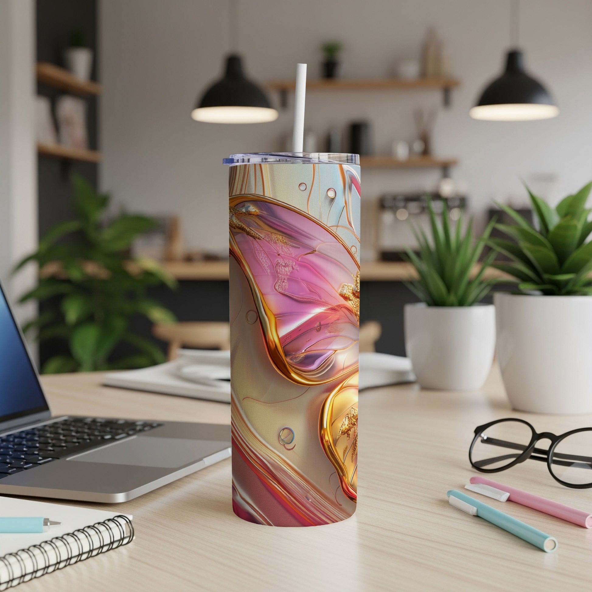 Abstract pink and gold swirls on a tumbler with straw on a desk.