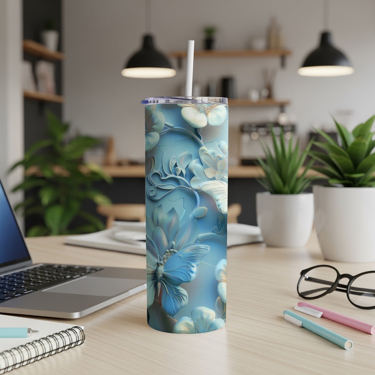Blue floral butterfly tumbler on a desk with laptop and pens.