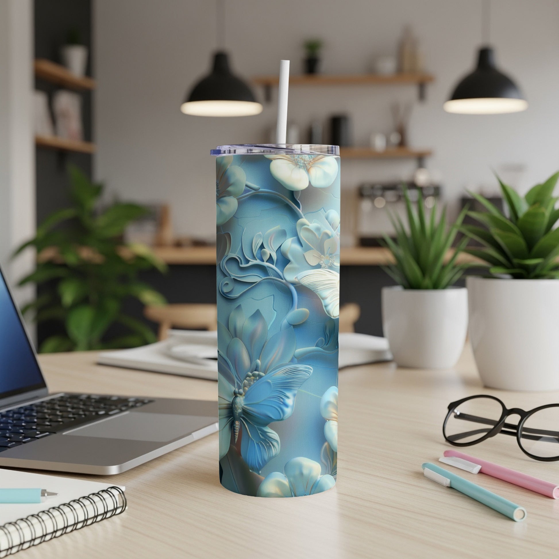 Blue floral butterfly tumbler on a desk with laptop and pens.