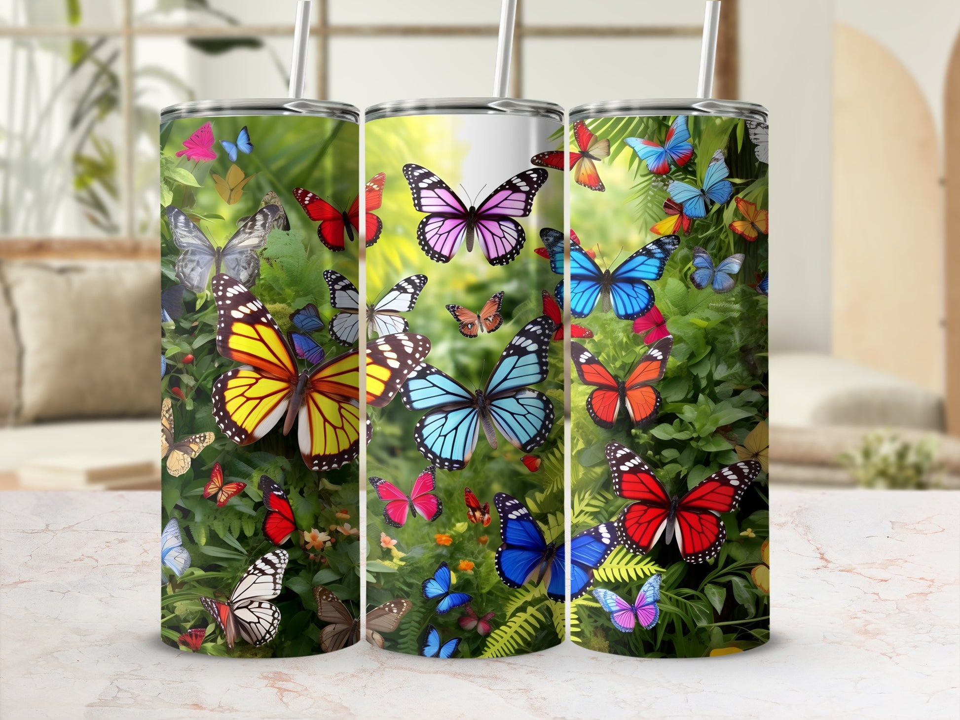 Three stainless steel tumblers with colorful butterfly designs, two with straws.