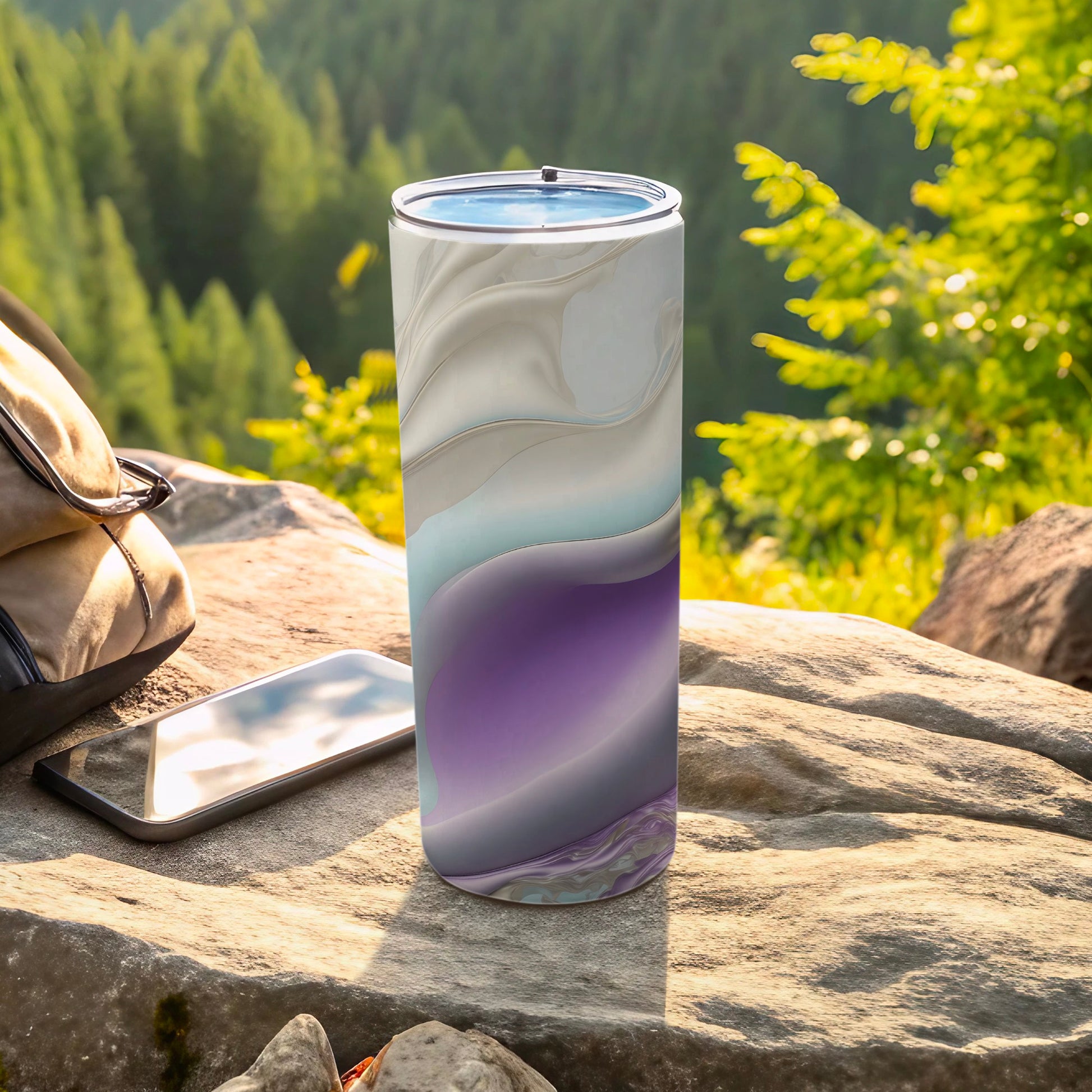 Abstract marbled tumbler with purple and blue swirls on a rock.