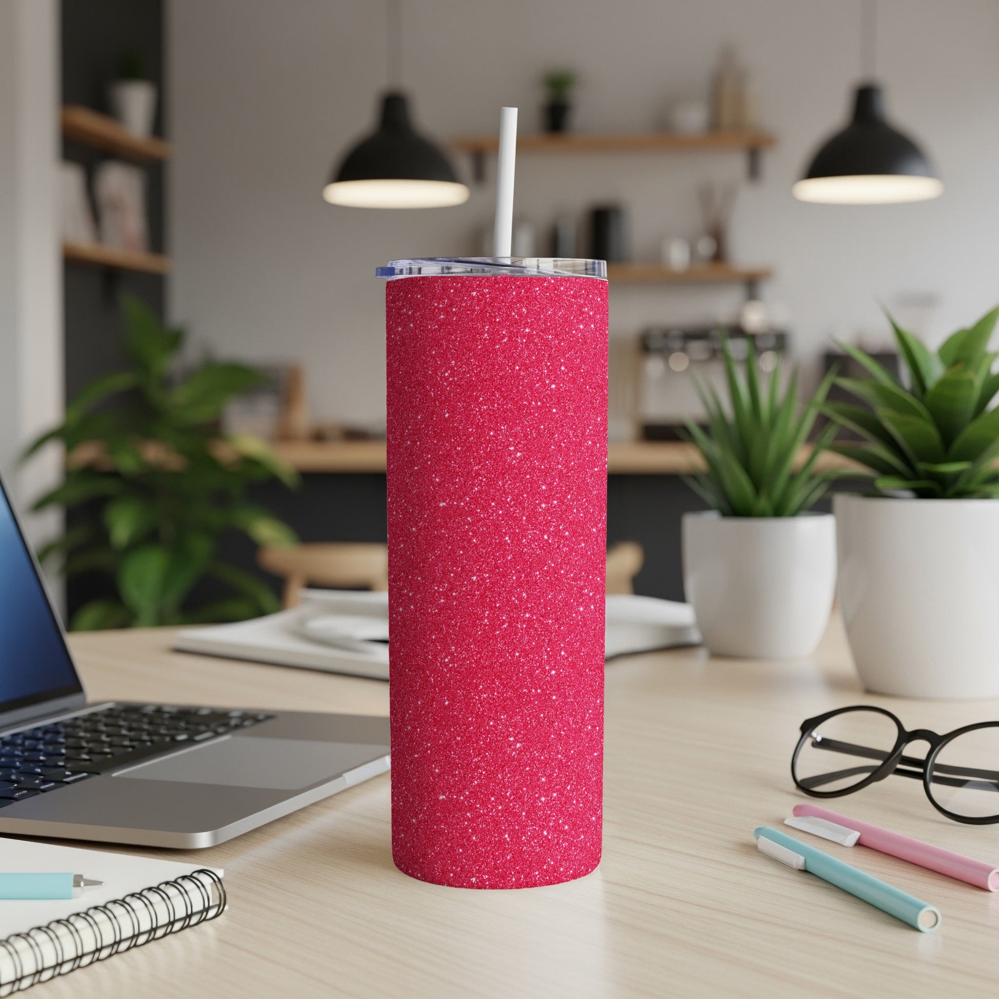 Glittery red skinny tumbler with white straw and lid on a desk.