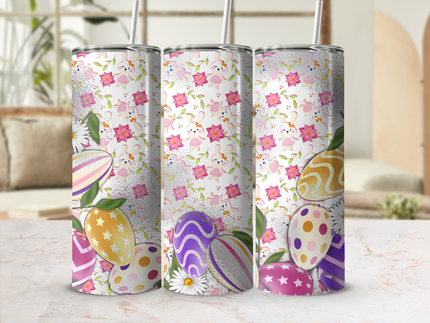 Three tumblers with Easter egg and bunny patterns on a marble surface.