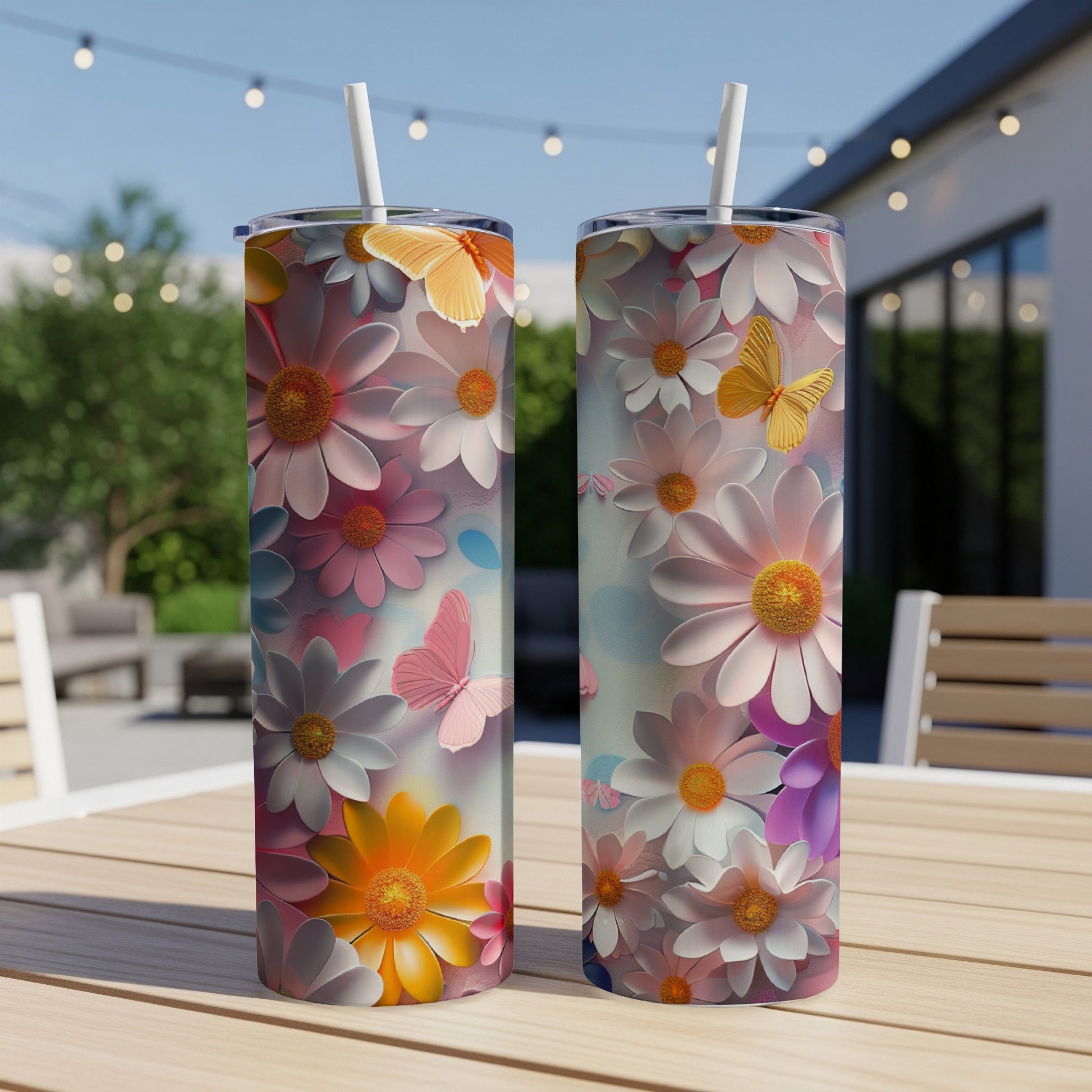 Two tumblers with floral and butterfly designs on a wooden table outdoors.
