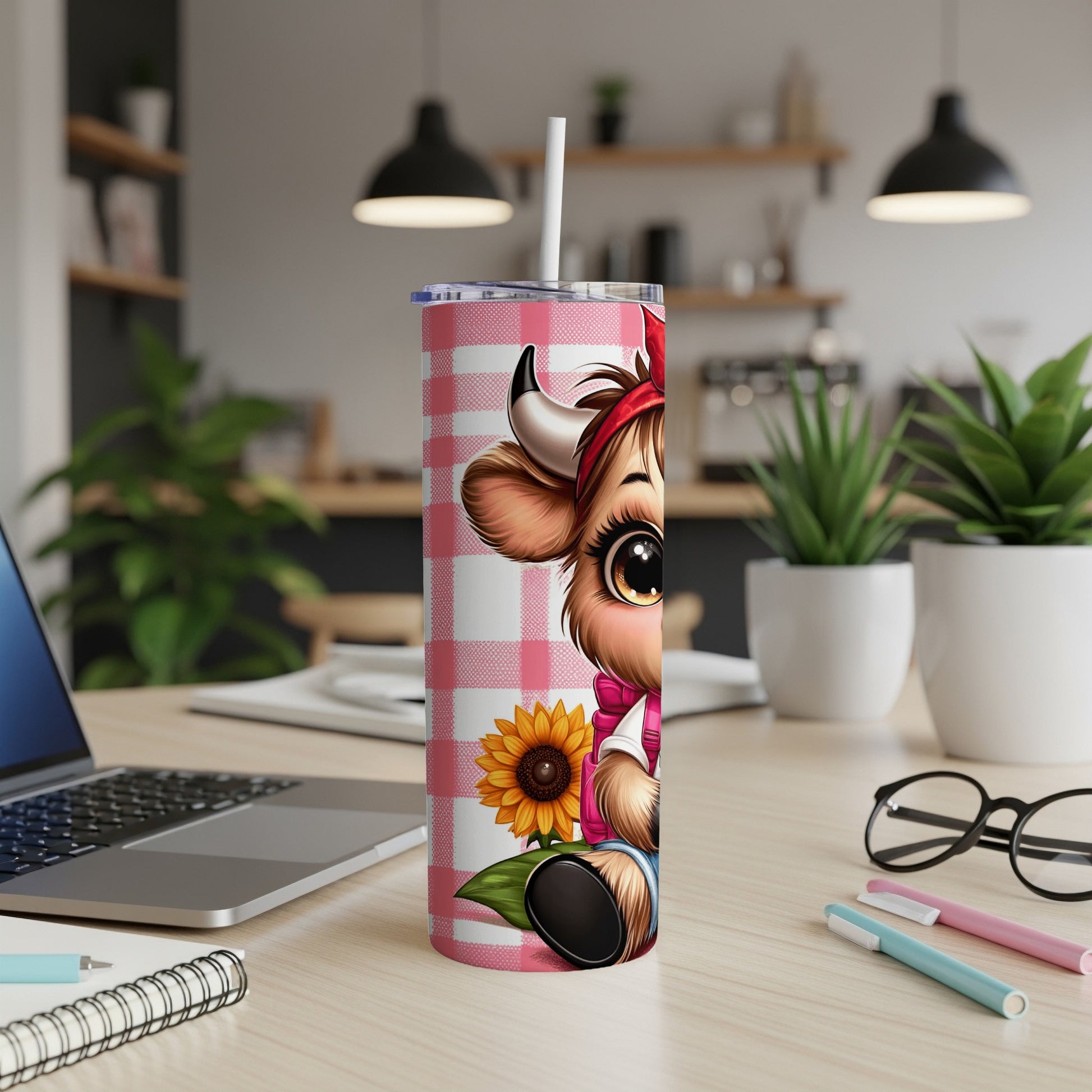 Cute cow tumbler with sunflower and plaid pattern on desk.