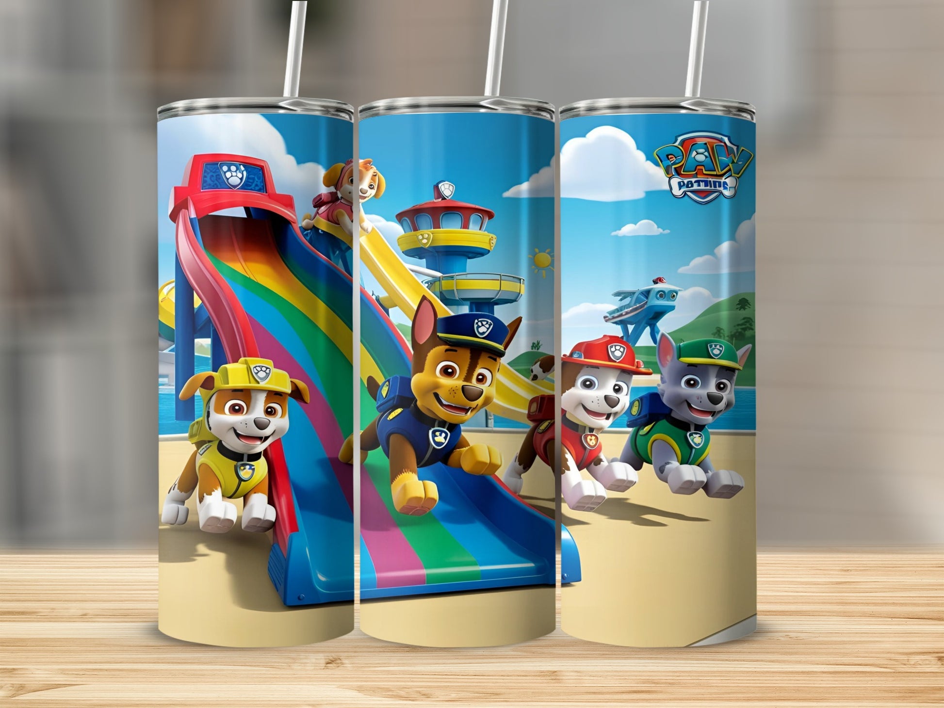 Paw Patrol characters slide down a rainbow on a beach under a blue sky.