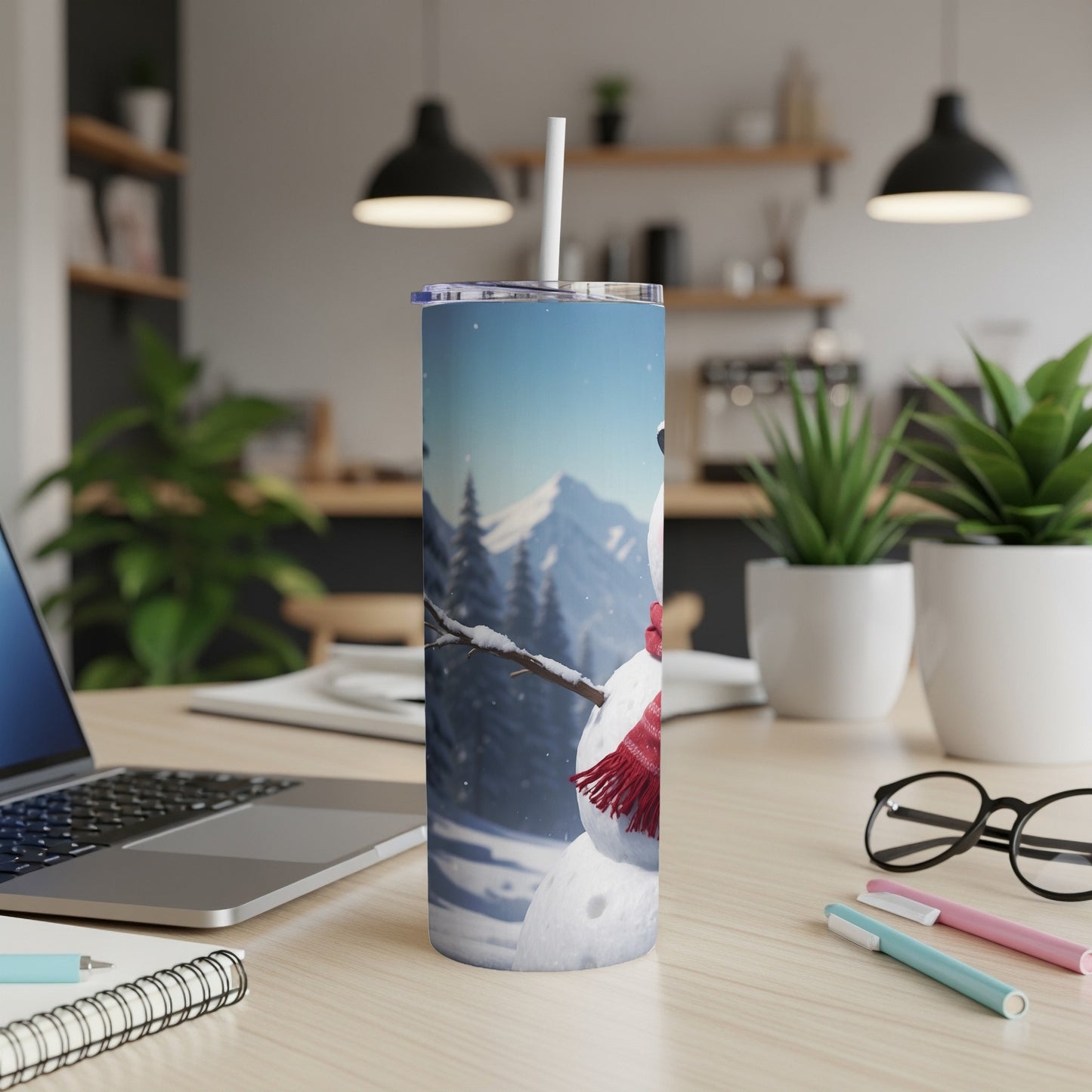 Snowman tumbler with red scarf on desk next to laptop.
