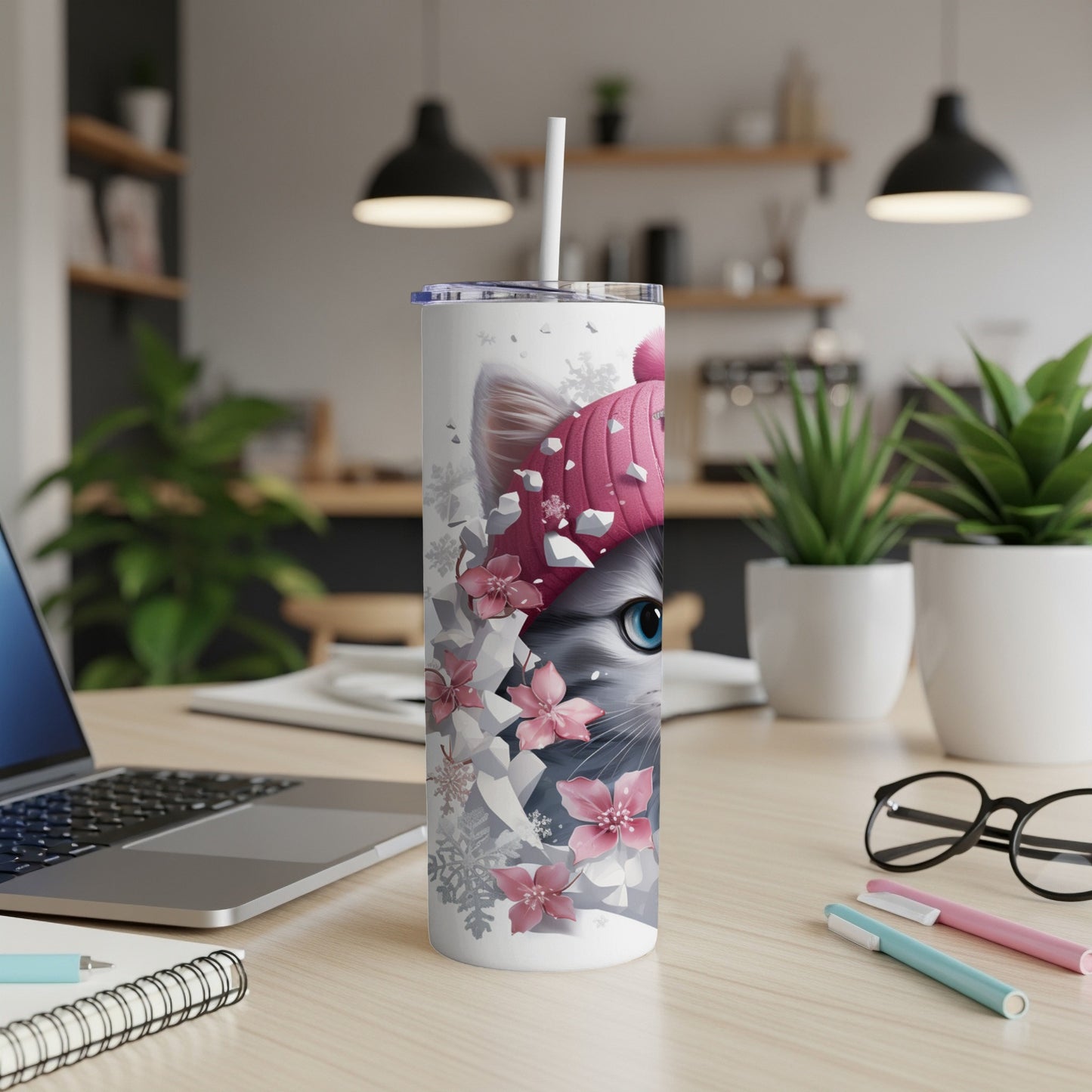White tumbler with pink cat design and snowflakes, on desk.