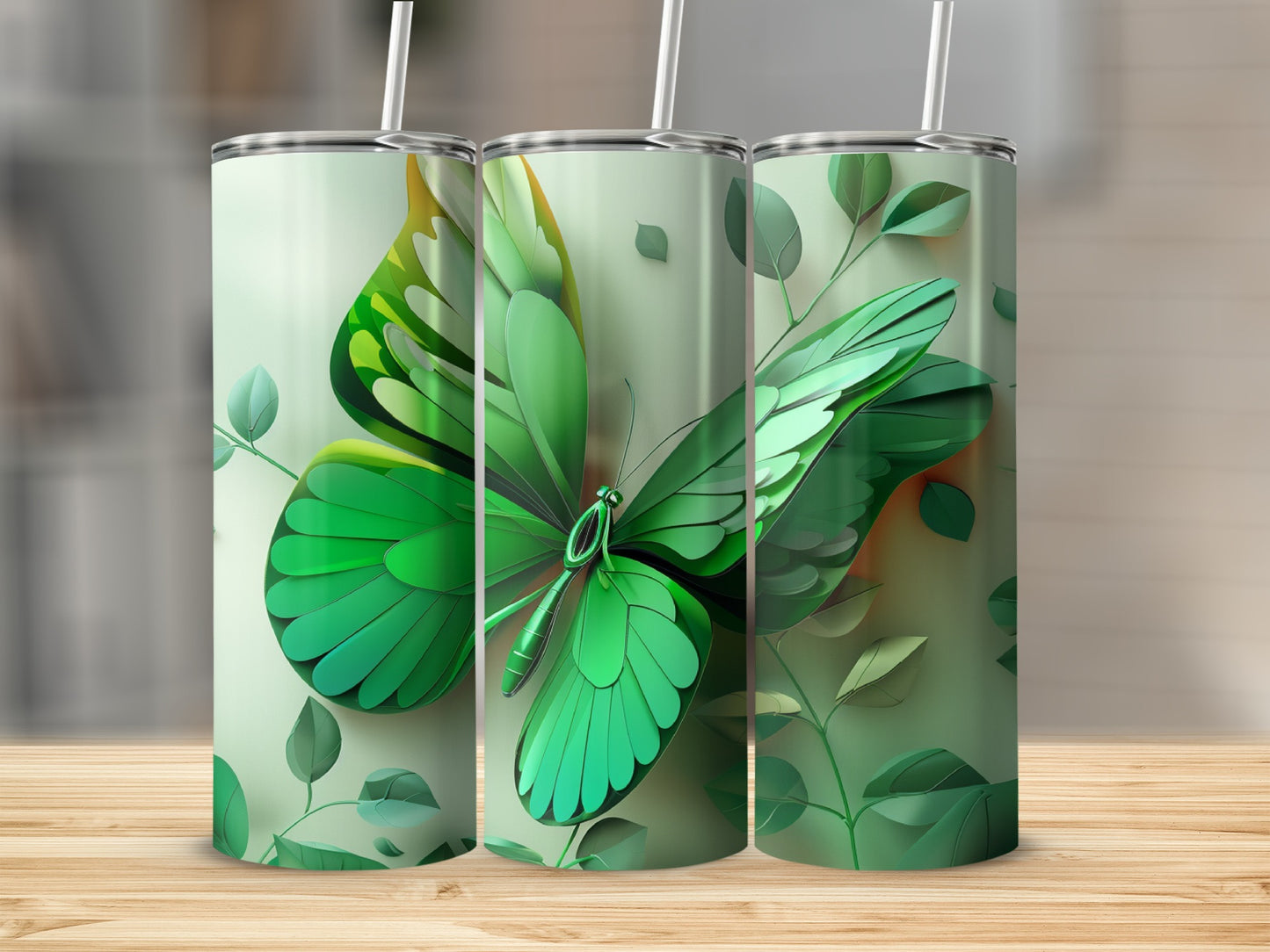 Green butterfly design on three tumblers with leaves on a wooden surface.