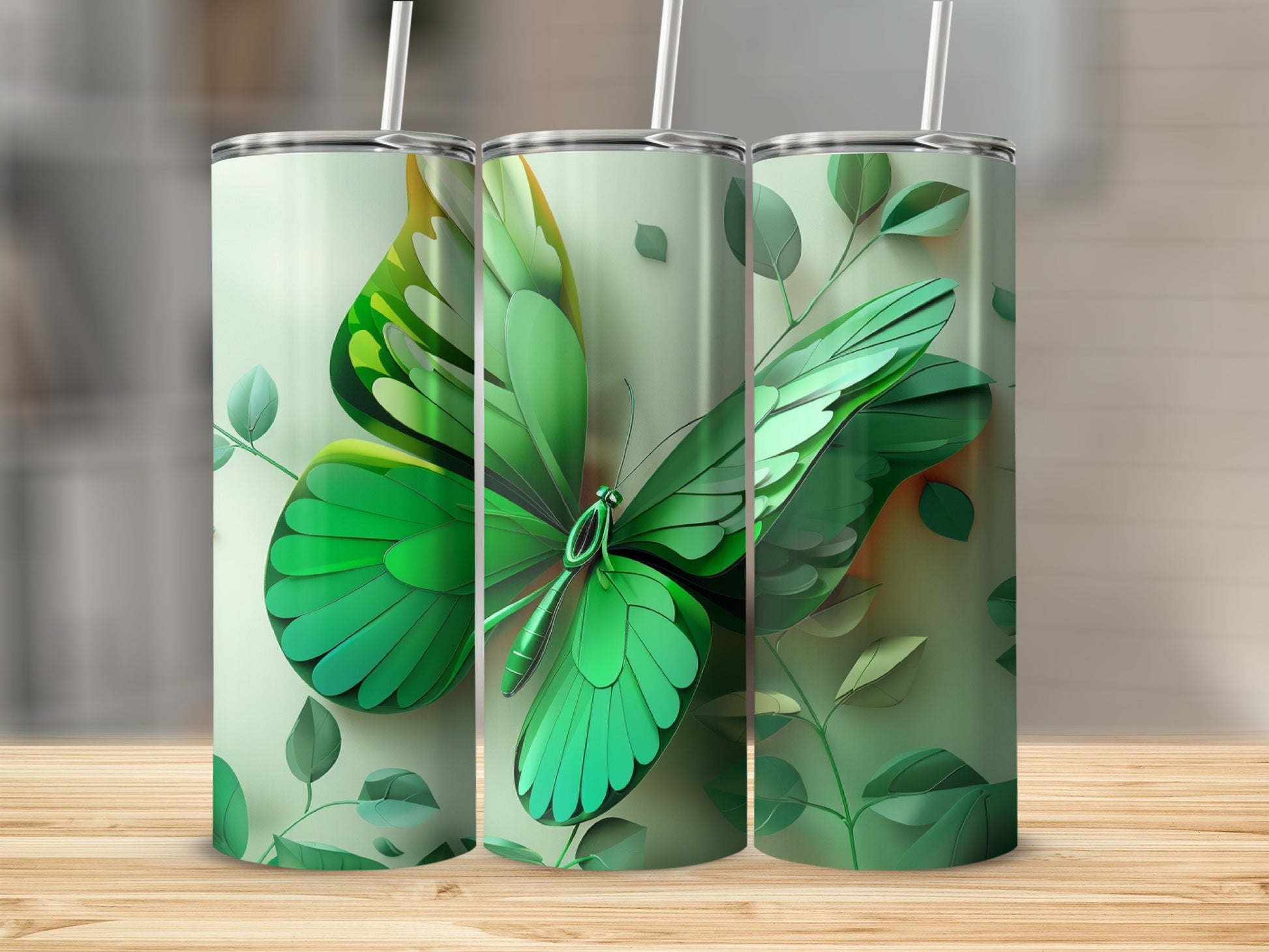 Green butterfly design on three tumblers with leaves on a wooden surface.