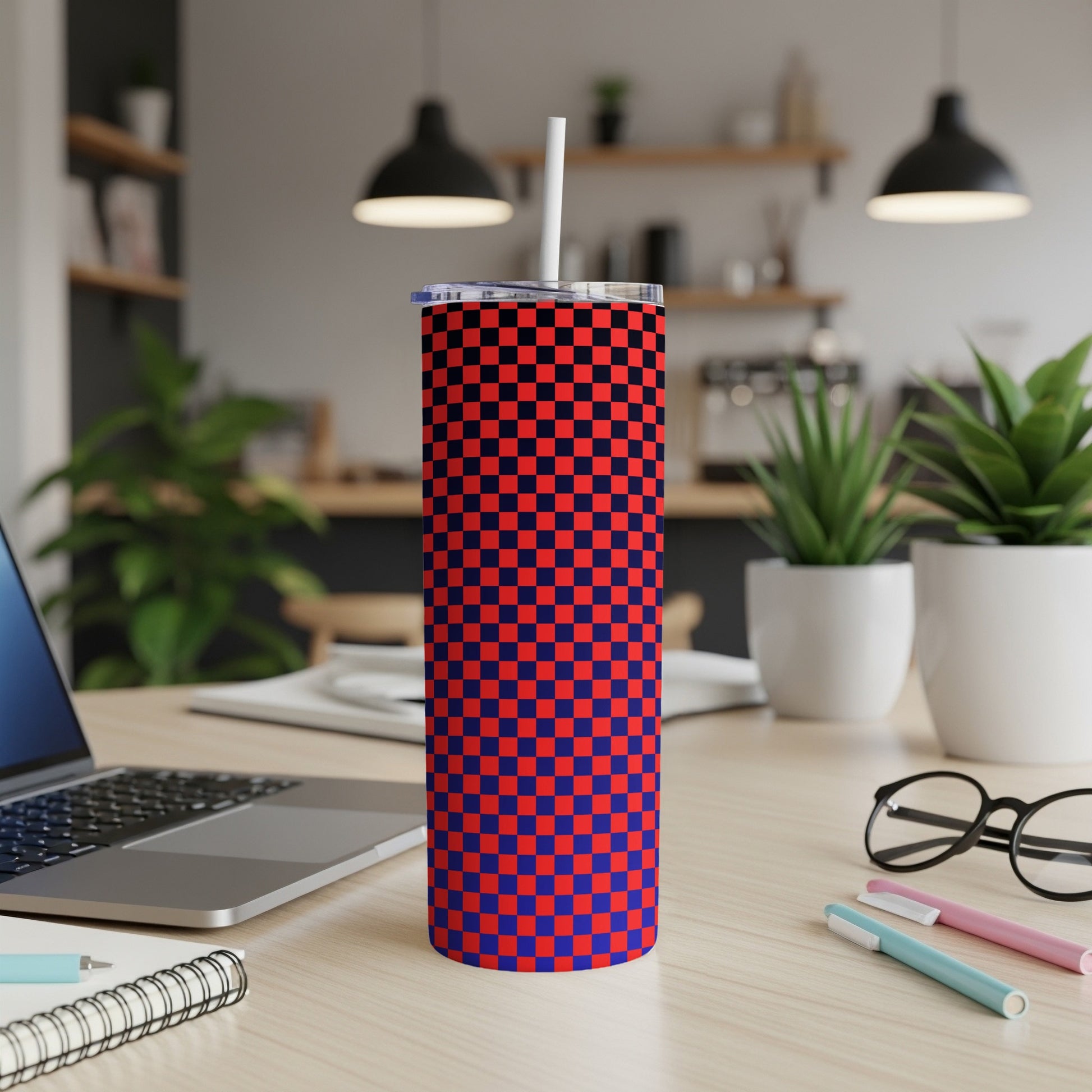 Red and blue checkered tumbler with straw on a desk.