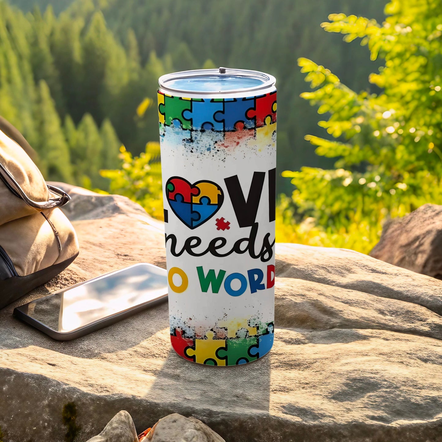Tumbler with colorful puzzle pieces and "Love needs no words" text.
