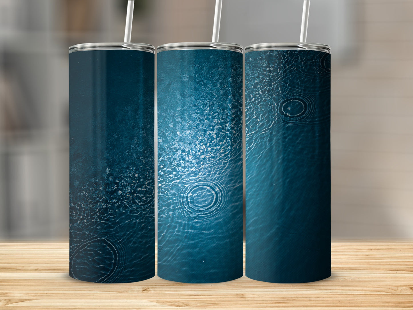 Three tumblers with a dark blue, rippling water design on a wooden surface.