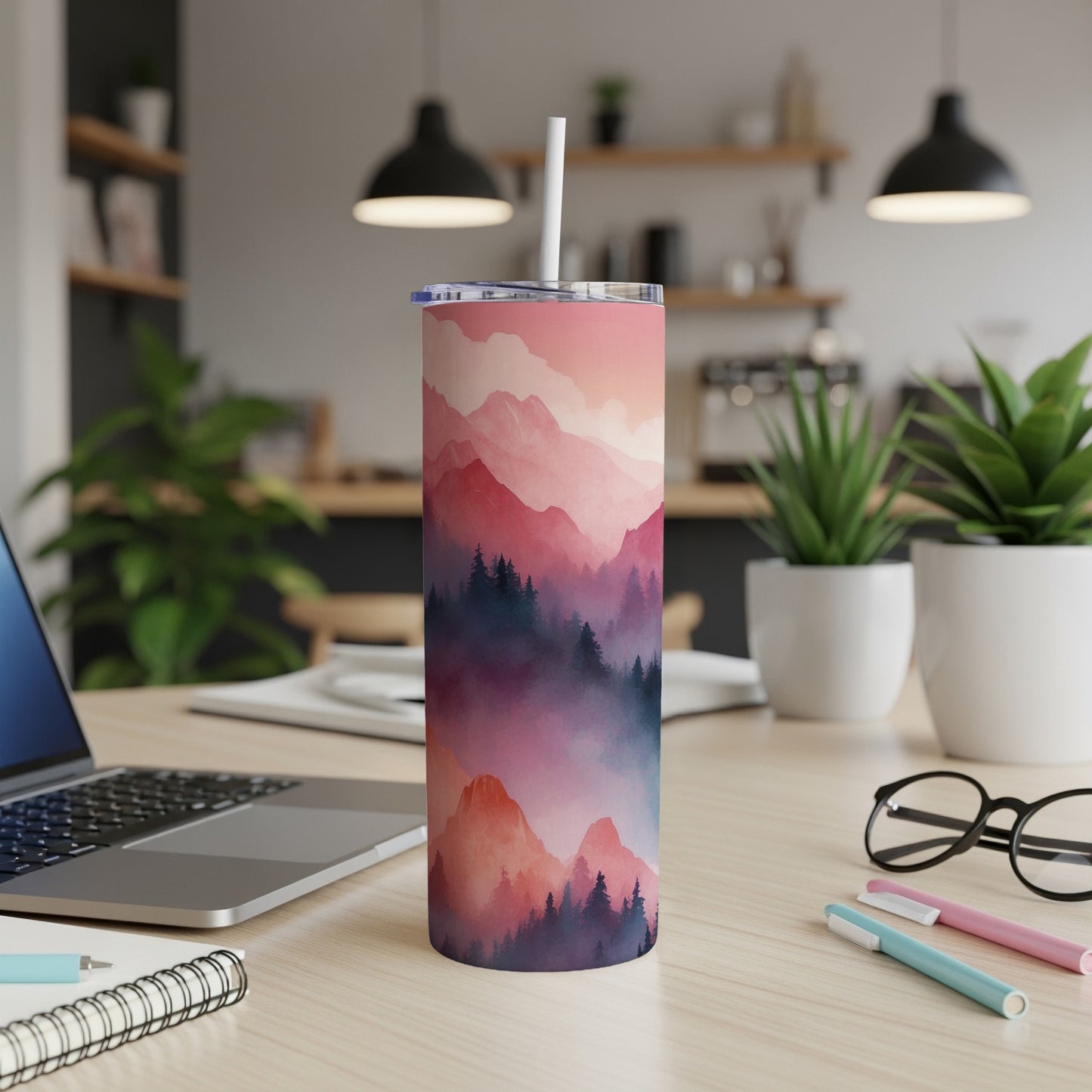 Pink and purple mountain landscape tumbler with straw on a desk.
