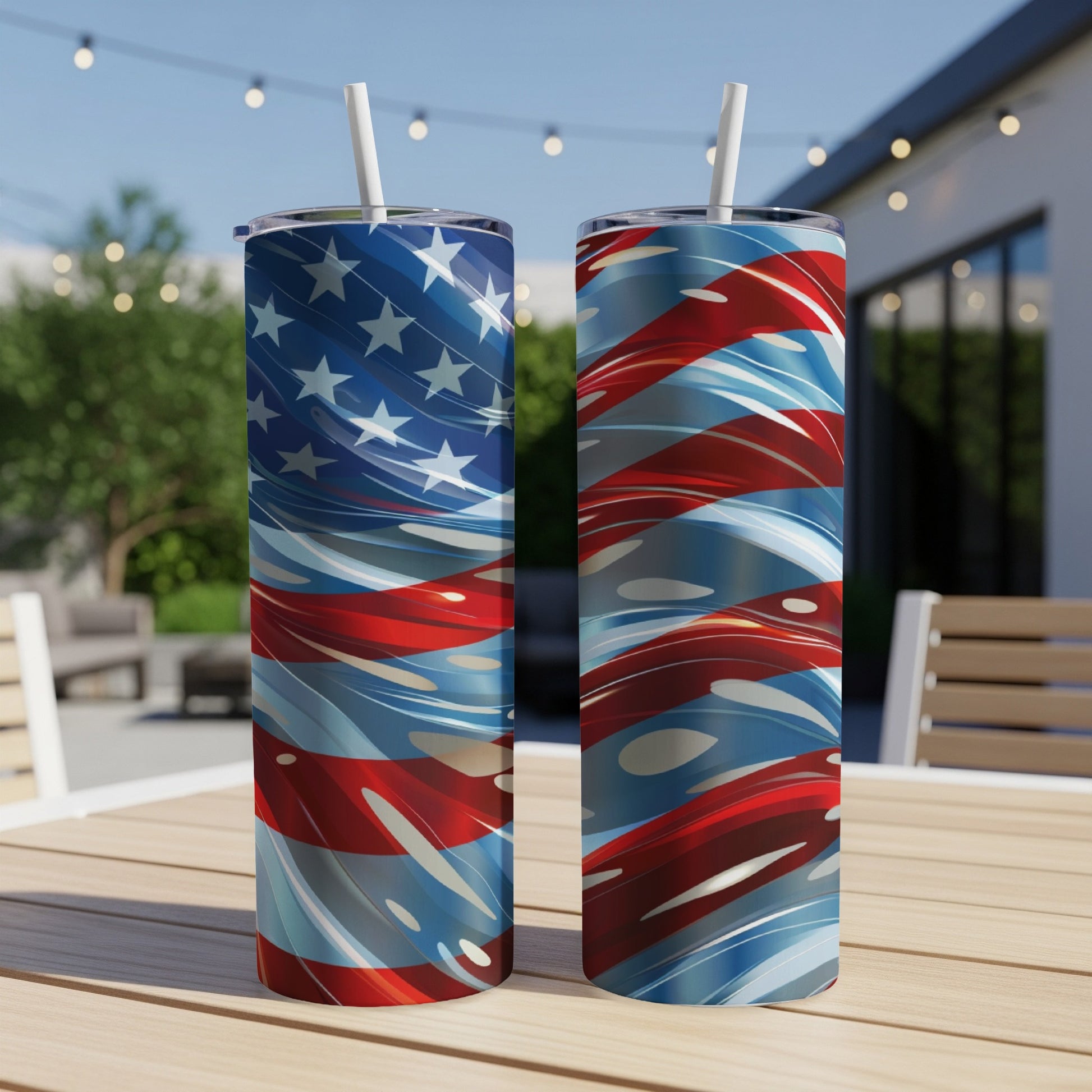 Two tumblers with a swirling American flag design sit on a wooden table outdoors.